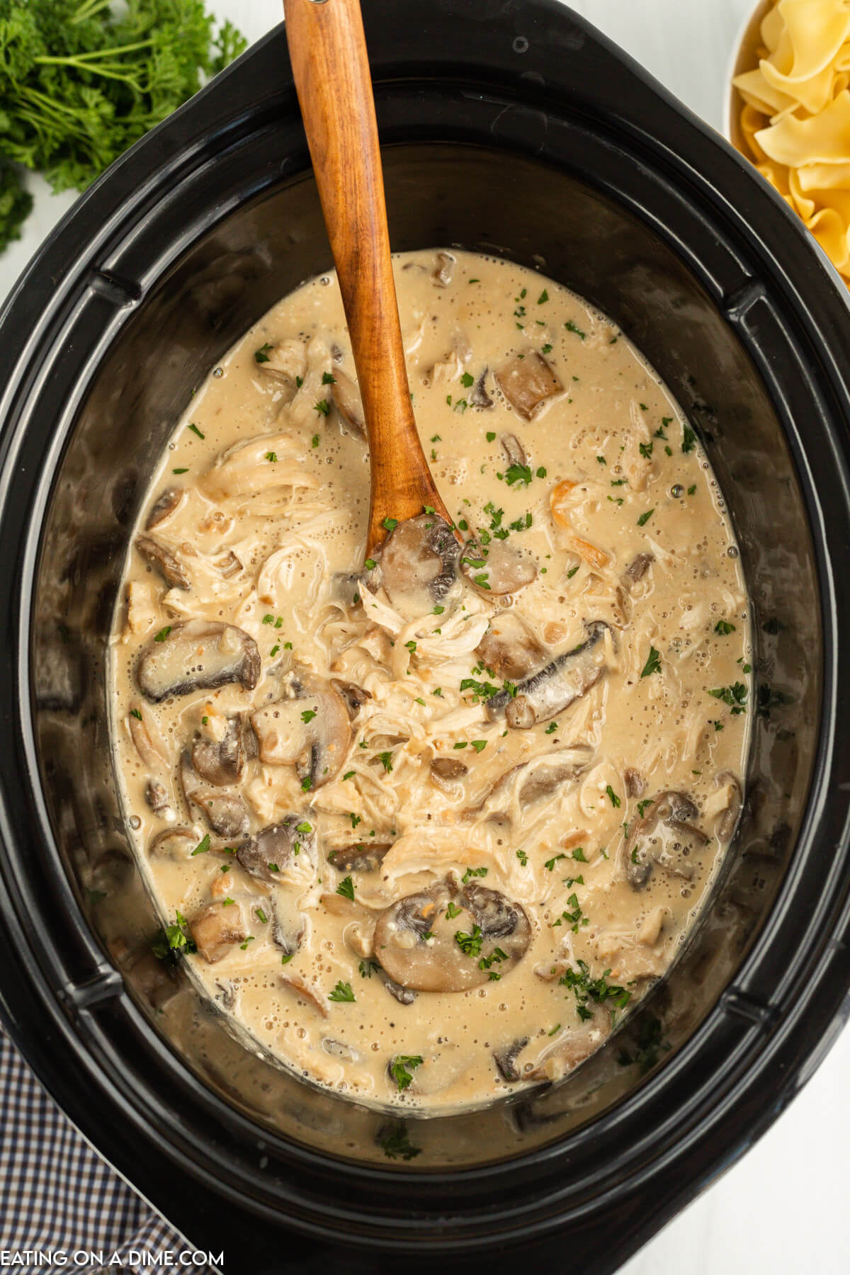 Chicken Stroganoff in the slow cooker with a wooden spoon