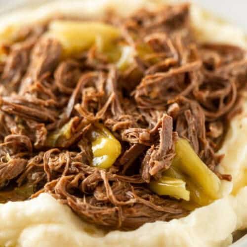 Mississippi Pot Roast-style shredded beef with pepperoncini peppers served on a bed of creamy mashed potatoes.