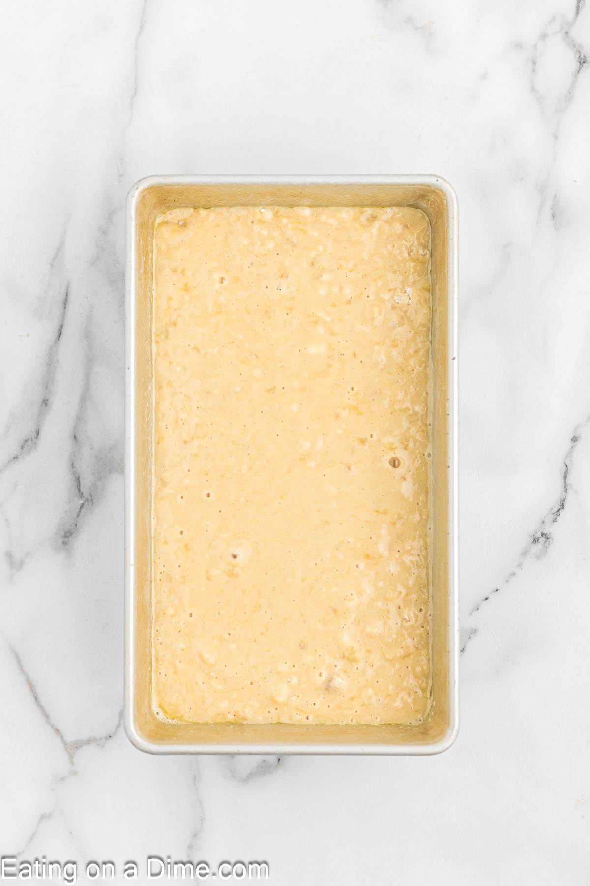 Pouring the banana bread batter in the loaf pan