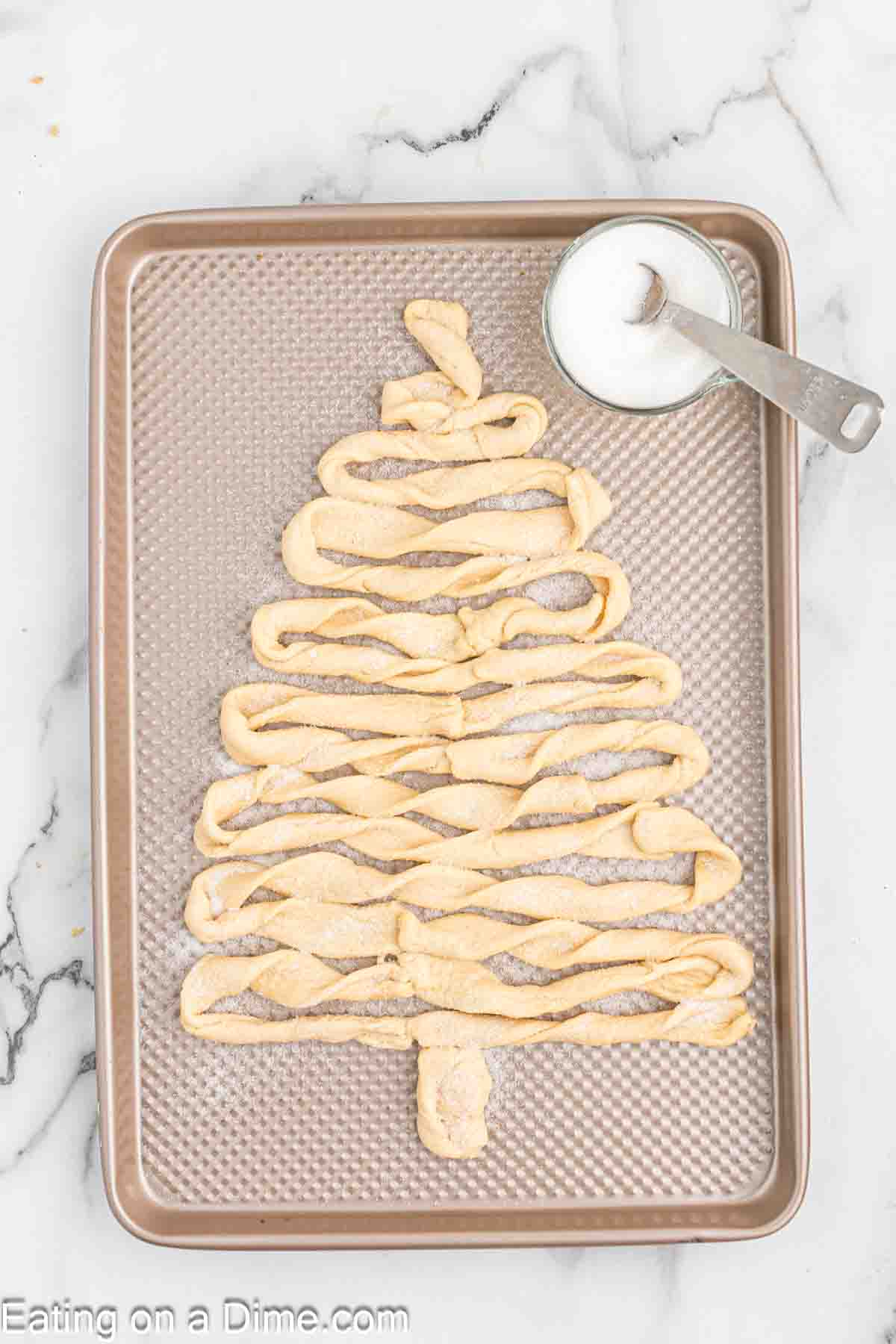 Twisted crescent rolls formed into a tree on a baking sheet. 