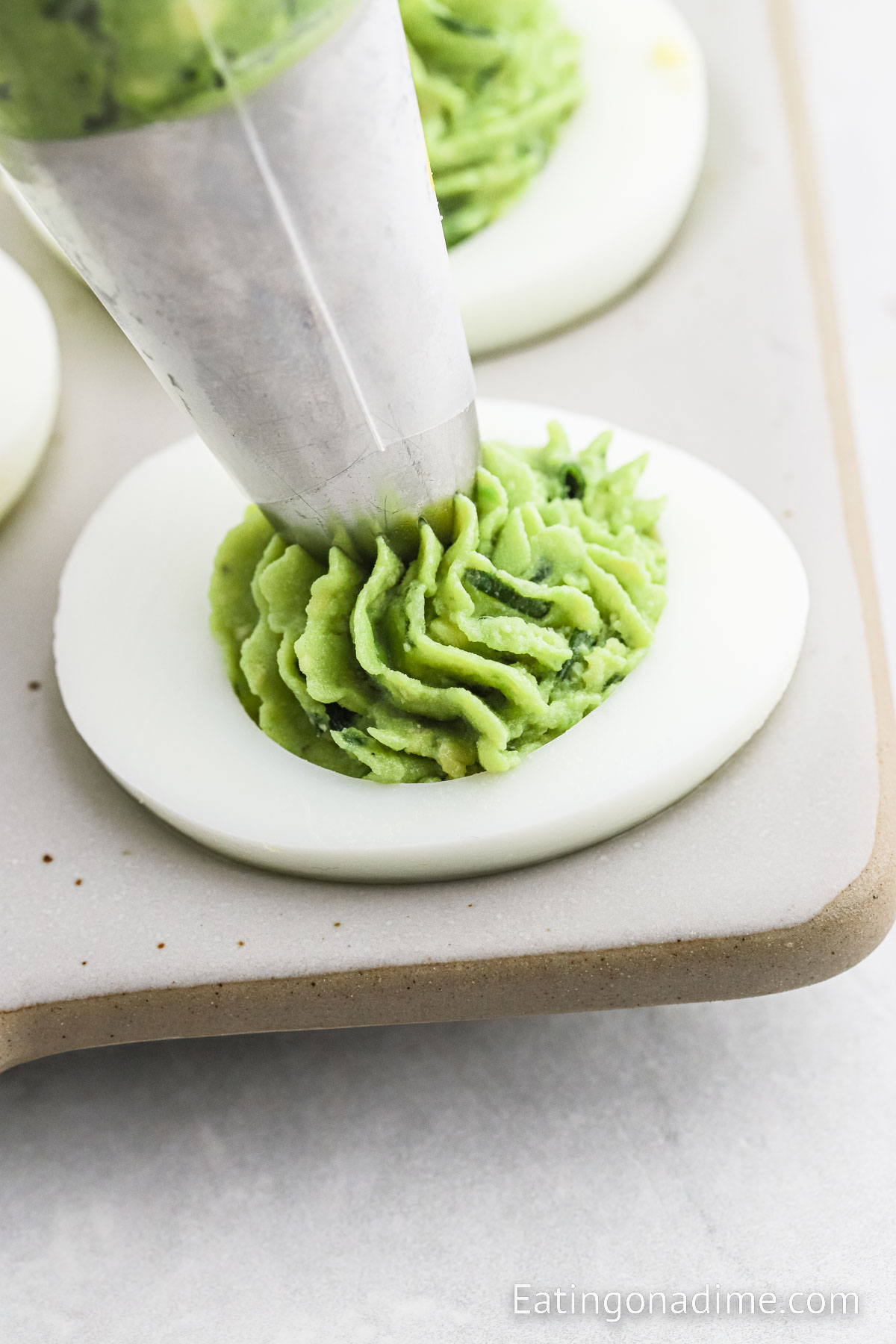 Adding the avocado filling to the egg white with a piping bag