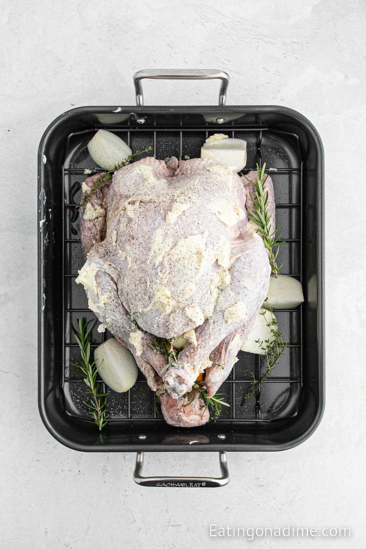 Covering the uncooked turkey with butter and seasoning in a roasting pan