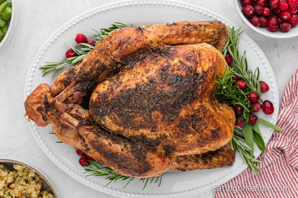 Grilled Whole Turkey on a platter with fresh herbs and berries