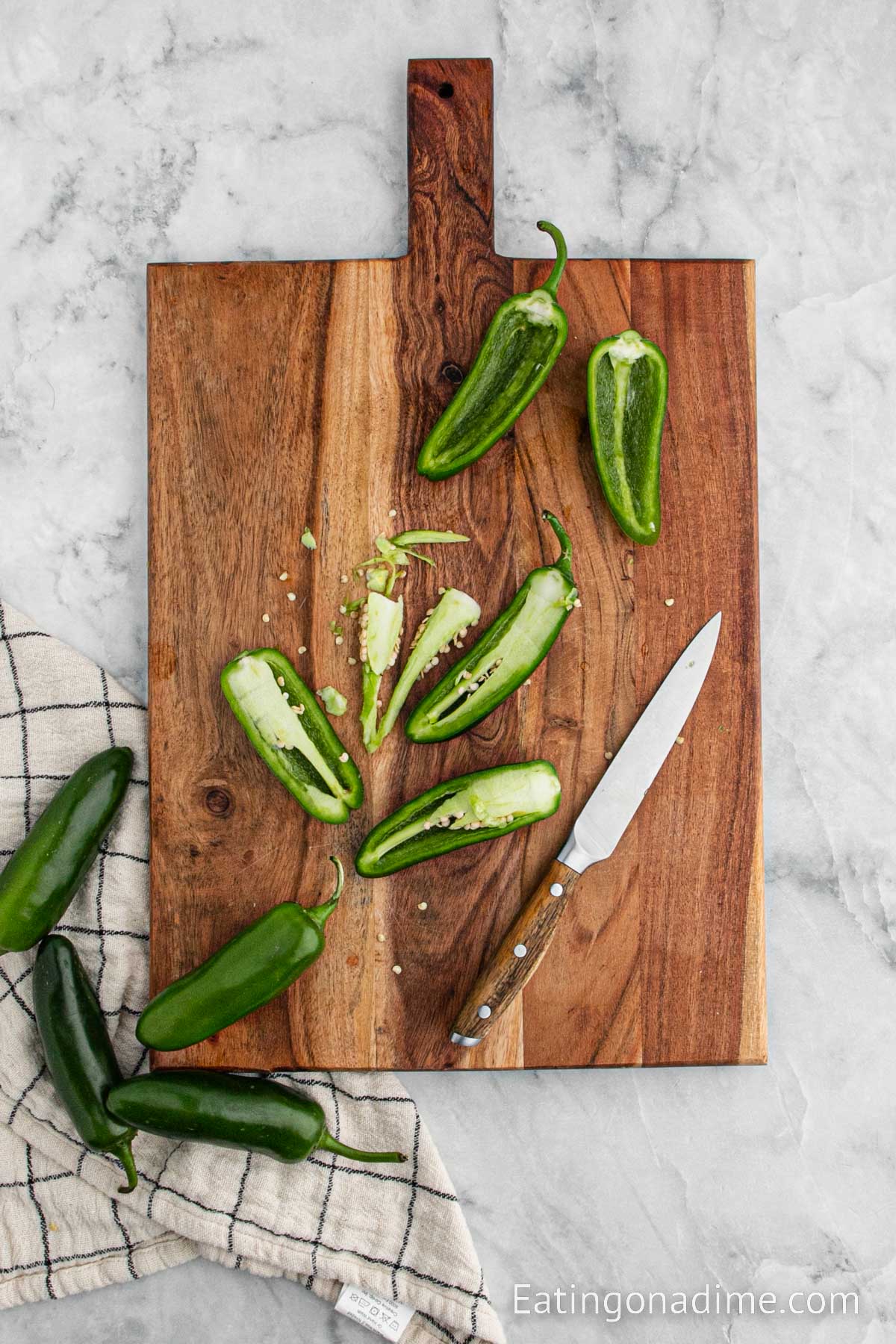 Slicing the jalapeno peppers on a cutting board with a knife