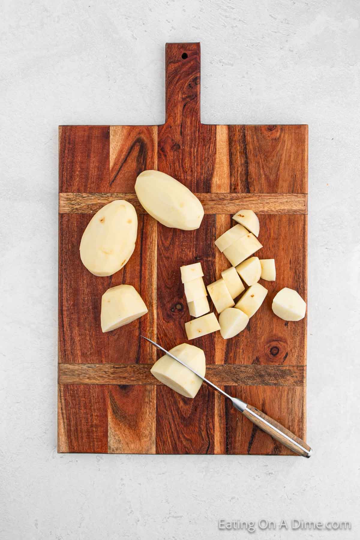 Peeled potatoes being cut on a cutting board