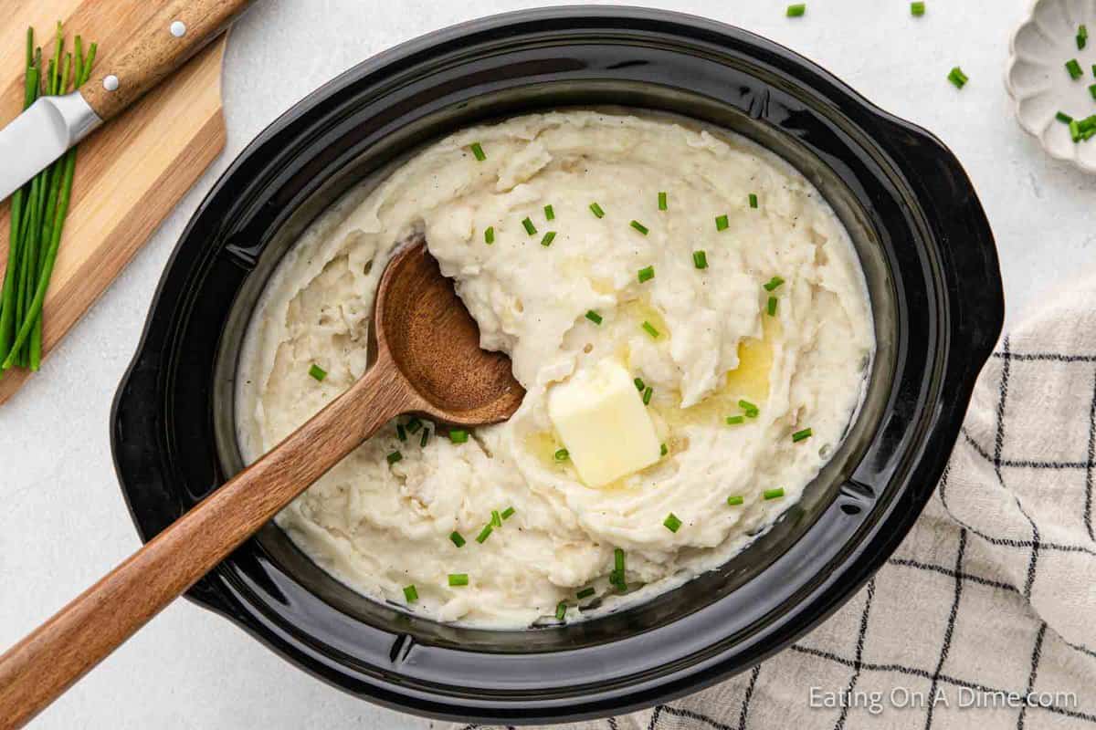 Mashed Potatoes in the crock pot with a wooden spoon