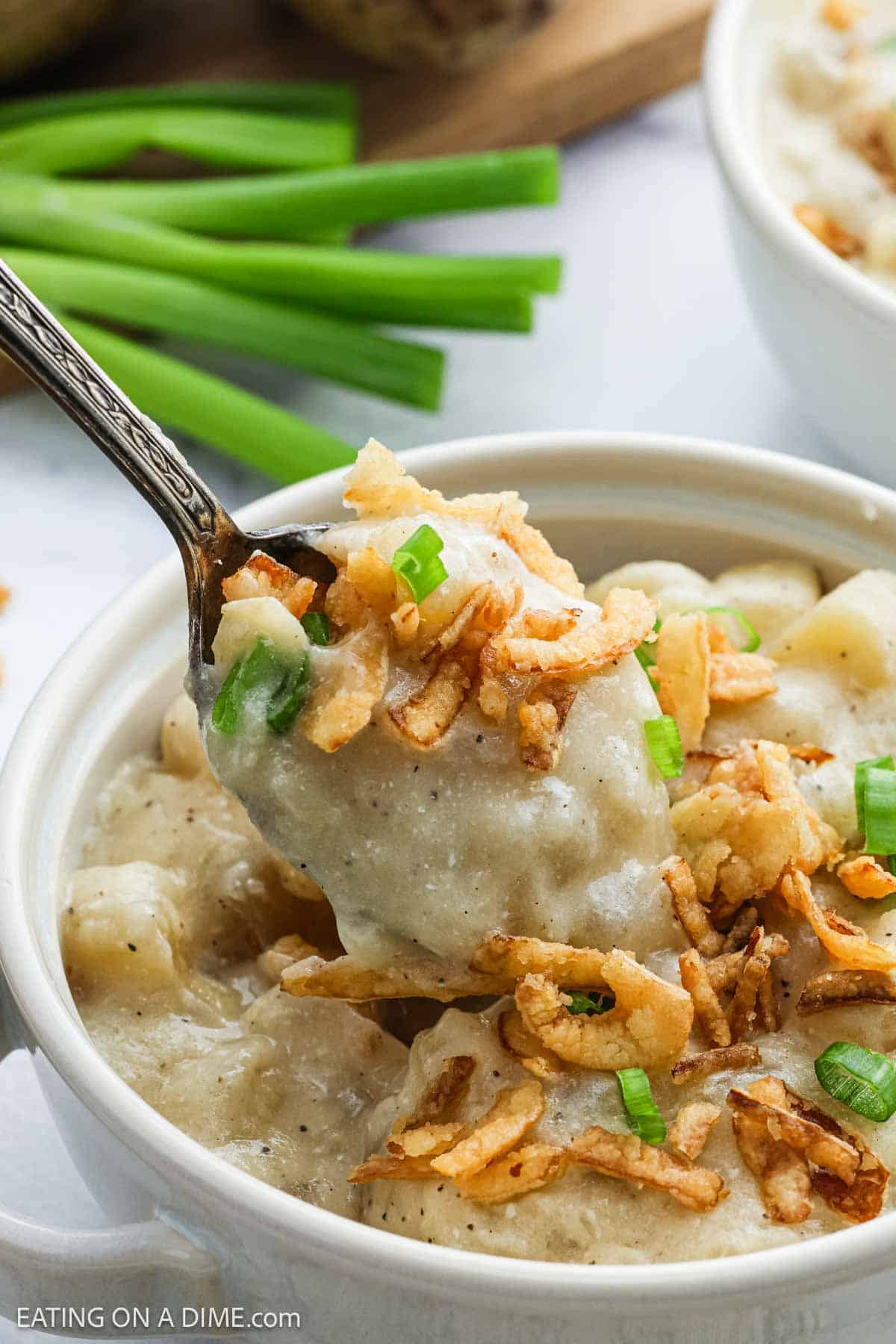Potato Soup in a bowl topped with chopped fried onions and green onions