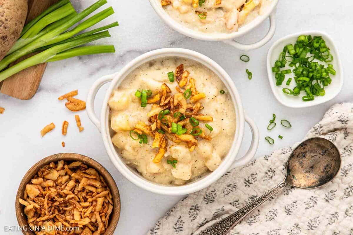 Potato Soup in a bowl with small bowls of fried onions and chopped green onions