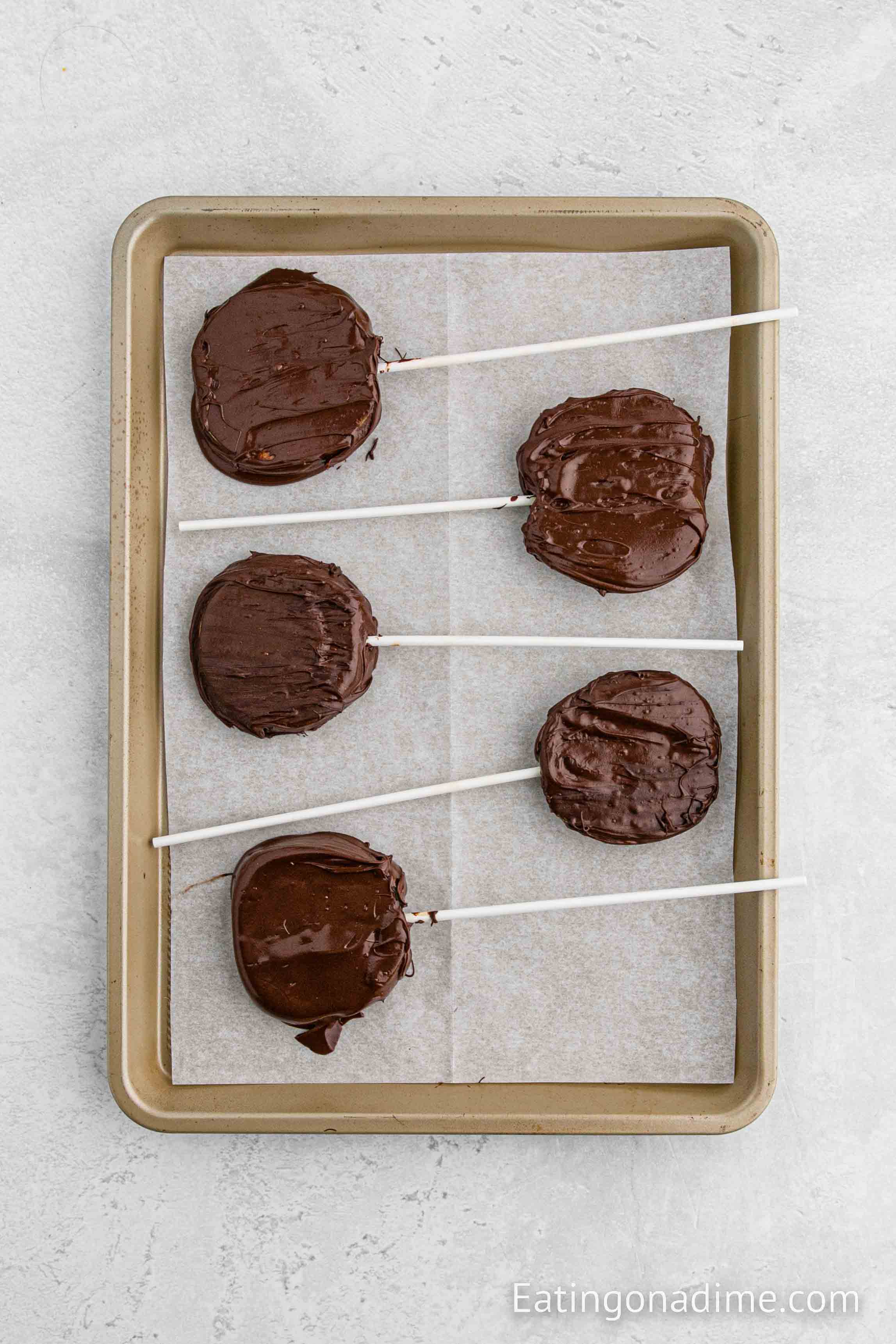Placing chocolate dipping apple slicing on a baking sheet