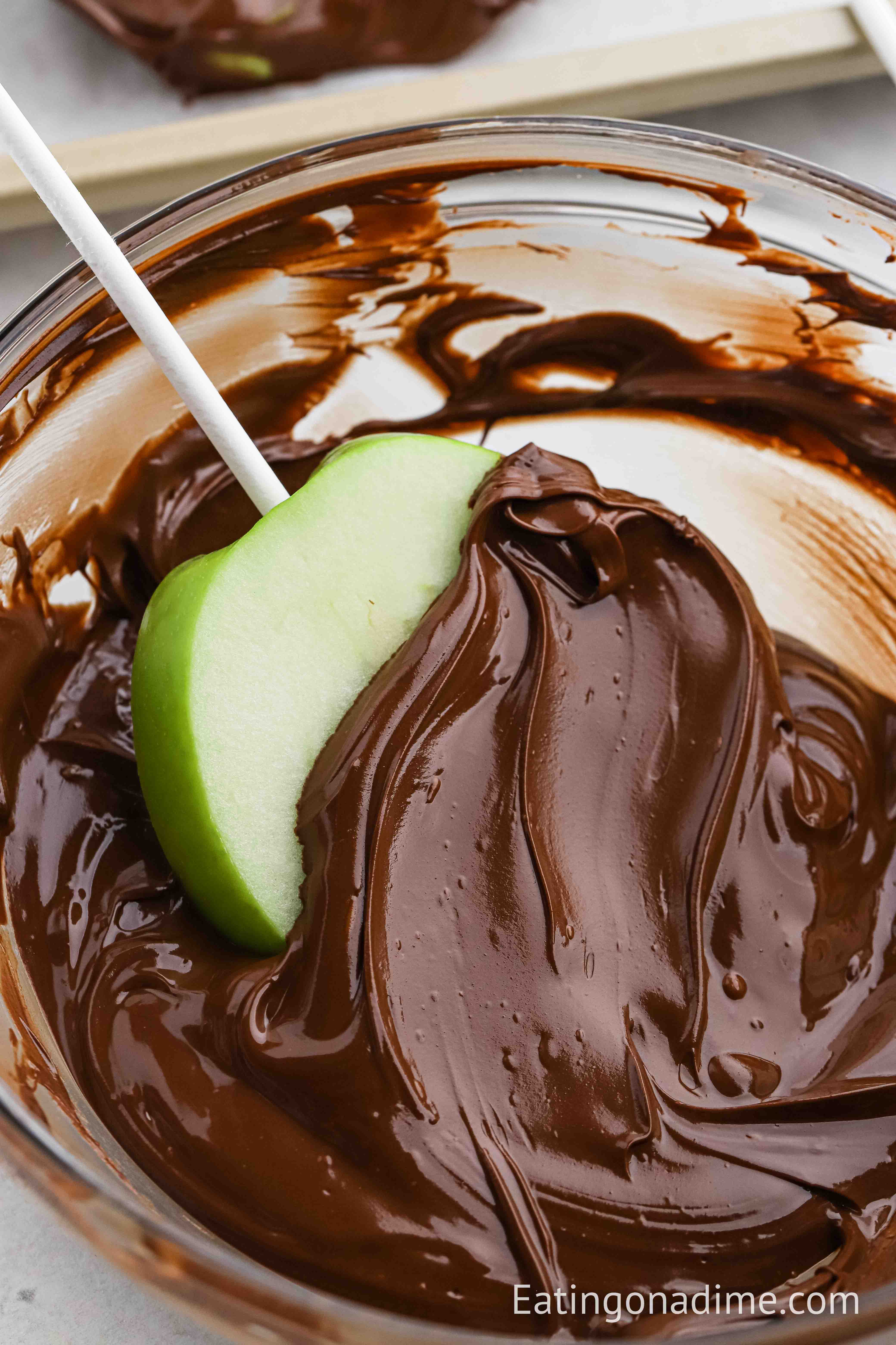 Dipping apple slices into melted chocolate