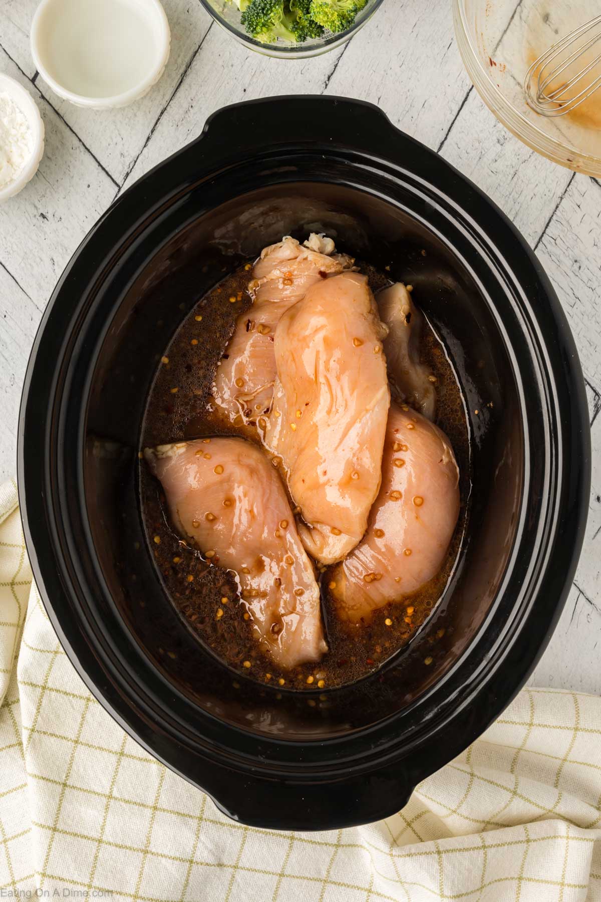 Pouring the sauce over the chicken in the slow cooker