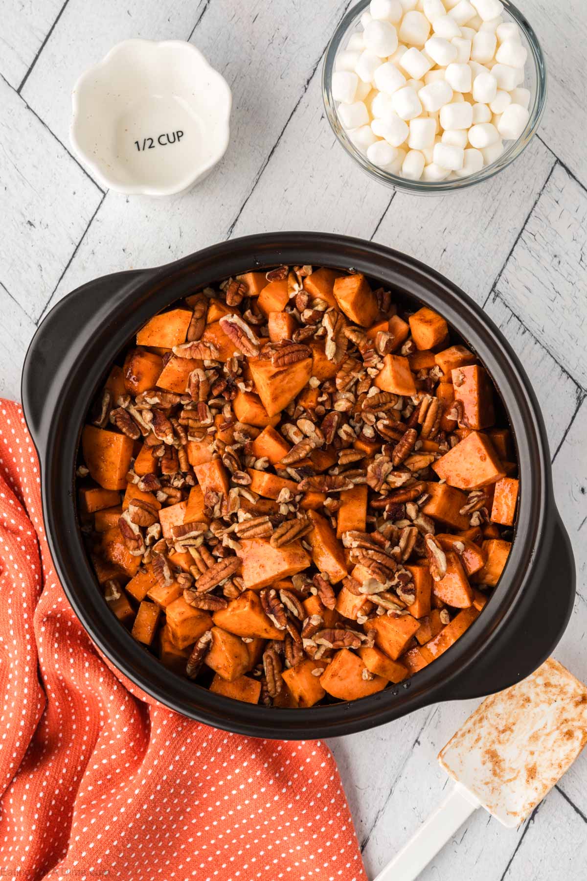 The chopped pecans poured on top of the sweet potatoes in the crock pot.  