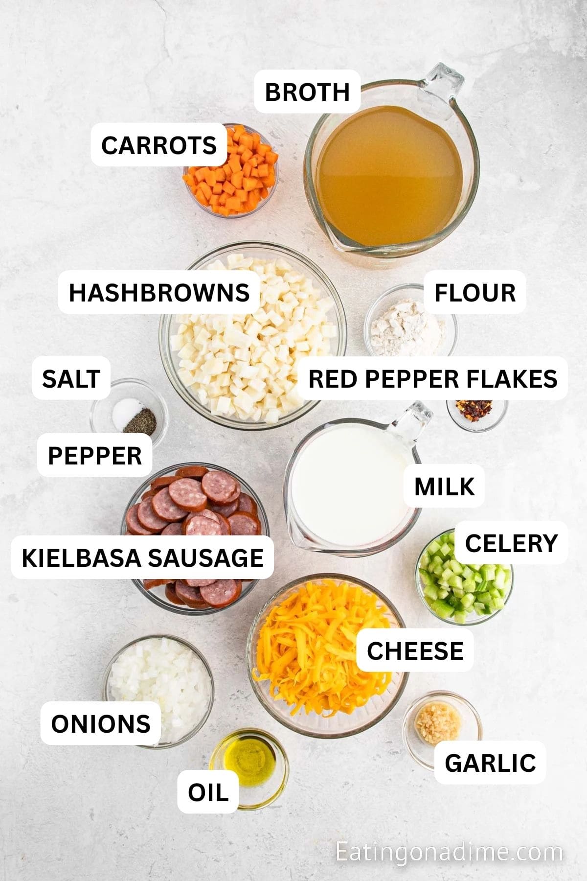 Ingredients needed to make potato and kielbasa soup - Olive oil, sausage, onion, carrots, celery, garlic, flour, chicken broth, hash browns red chili flakes, milk, salt, pepper, cheese.