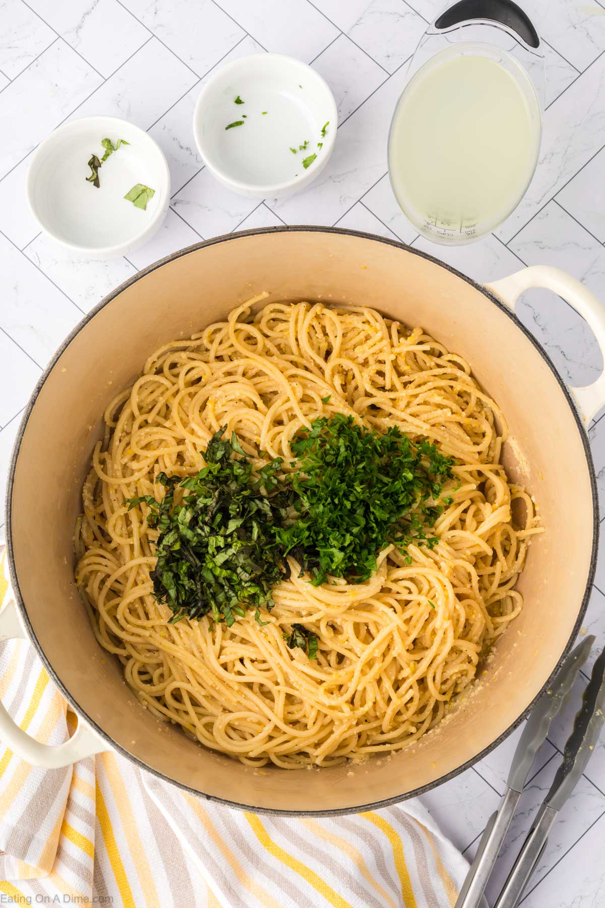 Topping the spaghetti with fresh basil and parsley