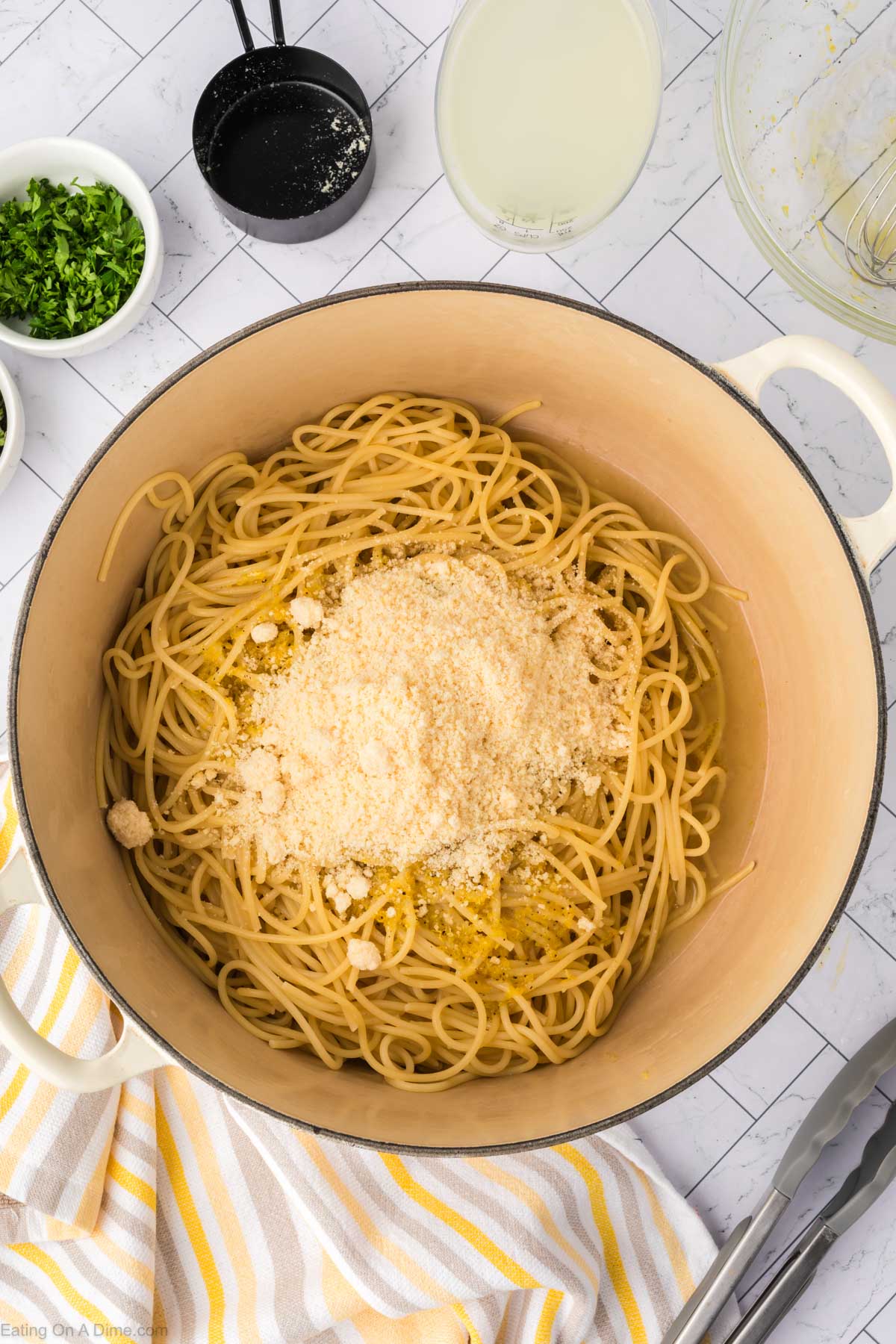 Cooked spaghetti in a large pot topped with parmesan cheese