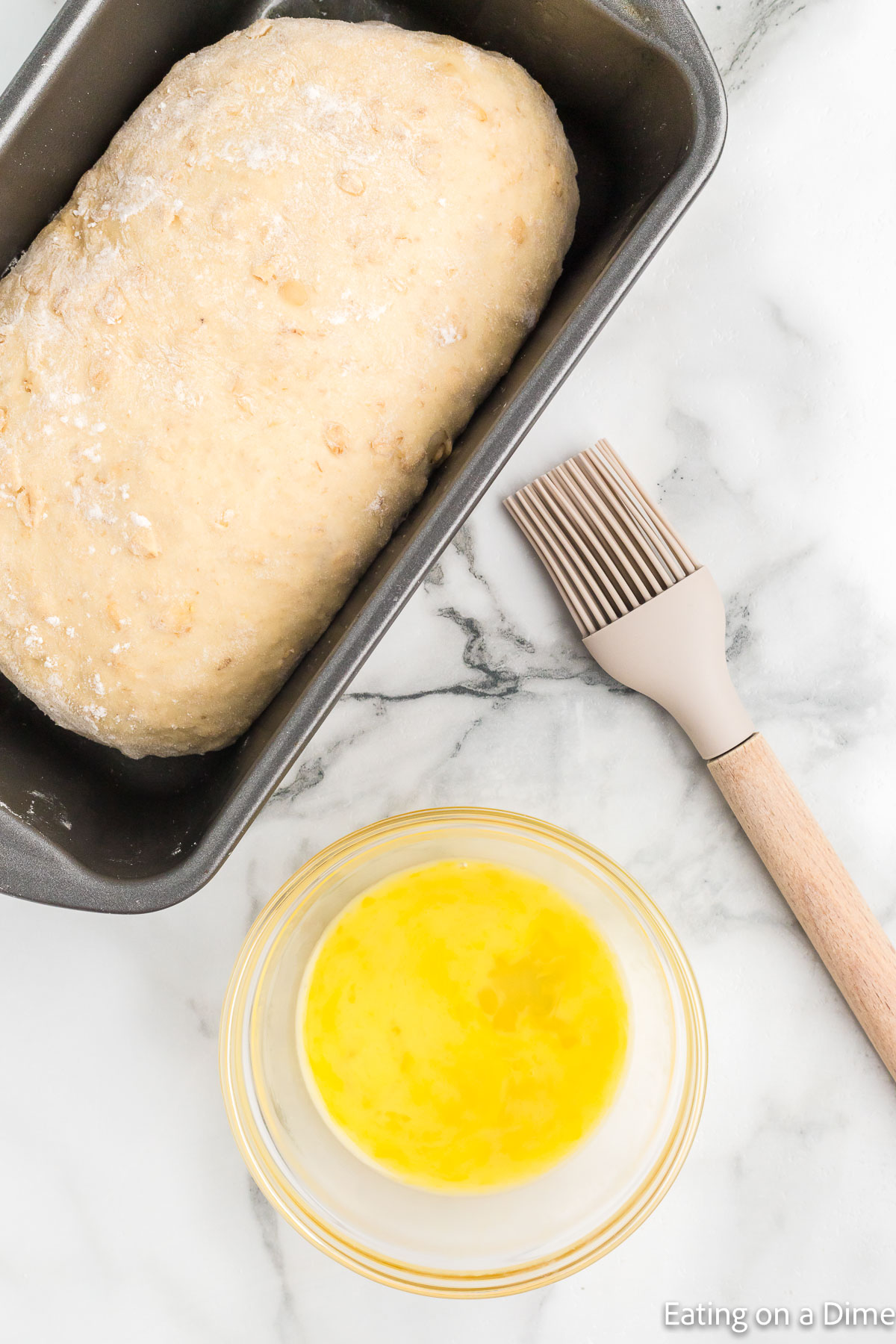 Topping the dough loaf in the pan with melted butter