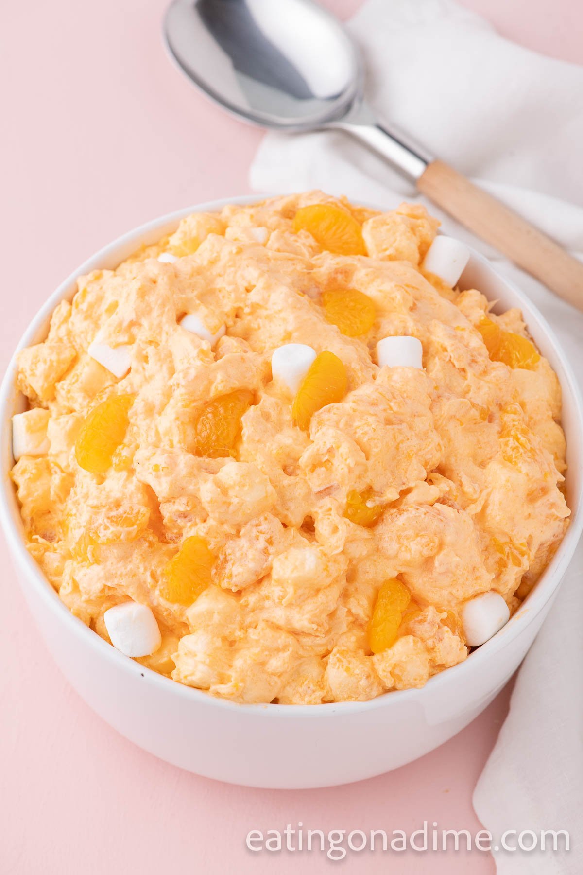 Orange Fluff in a white bowl topped with mandarin oranges and mini marshmallows