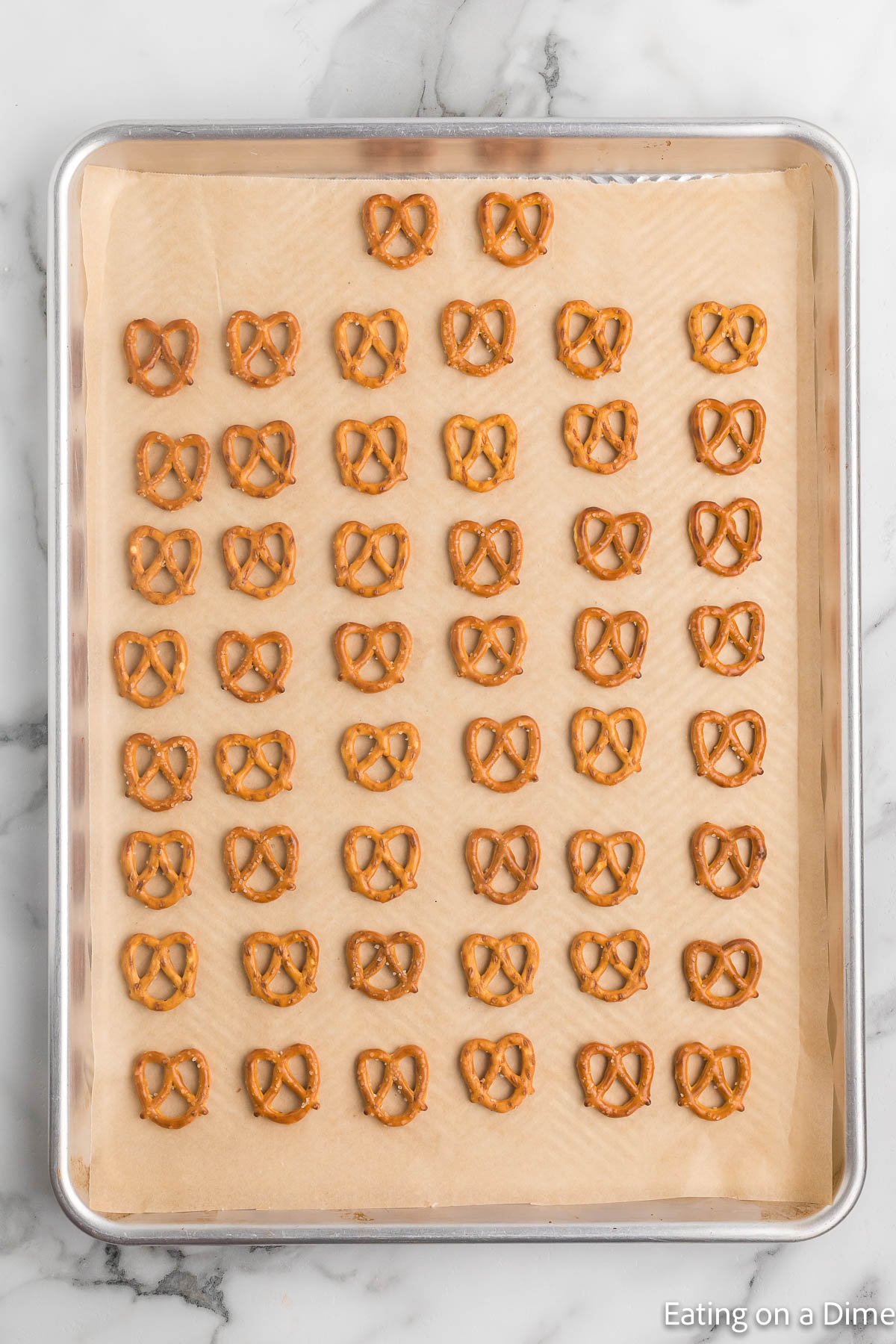 Placing a layer of pretzel on a baking sheet lined with parchment paper