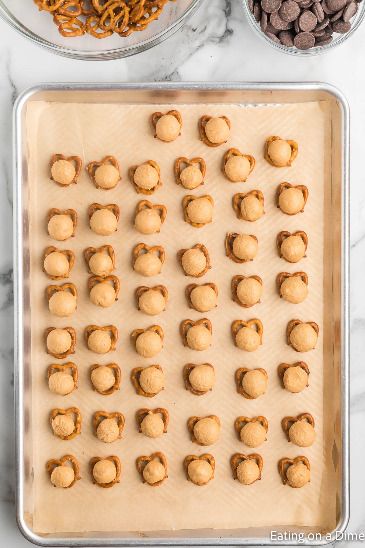 Topping the pretzels on the baking sheet with a peanut butter ball