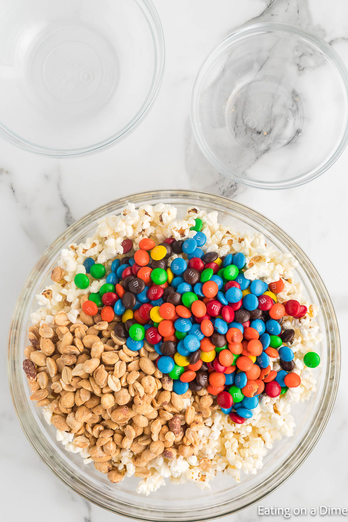 Combining the popcorn, nuts and M&M in a bowl