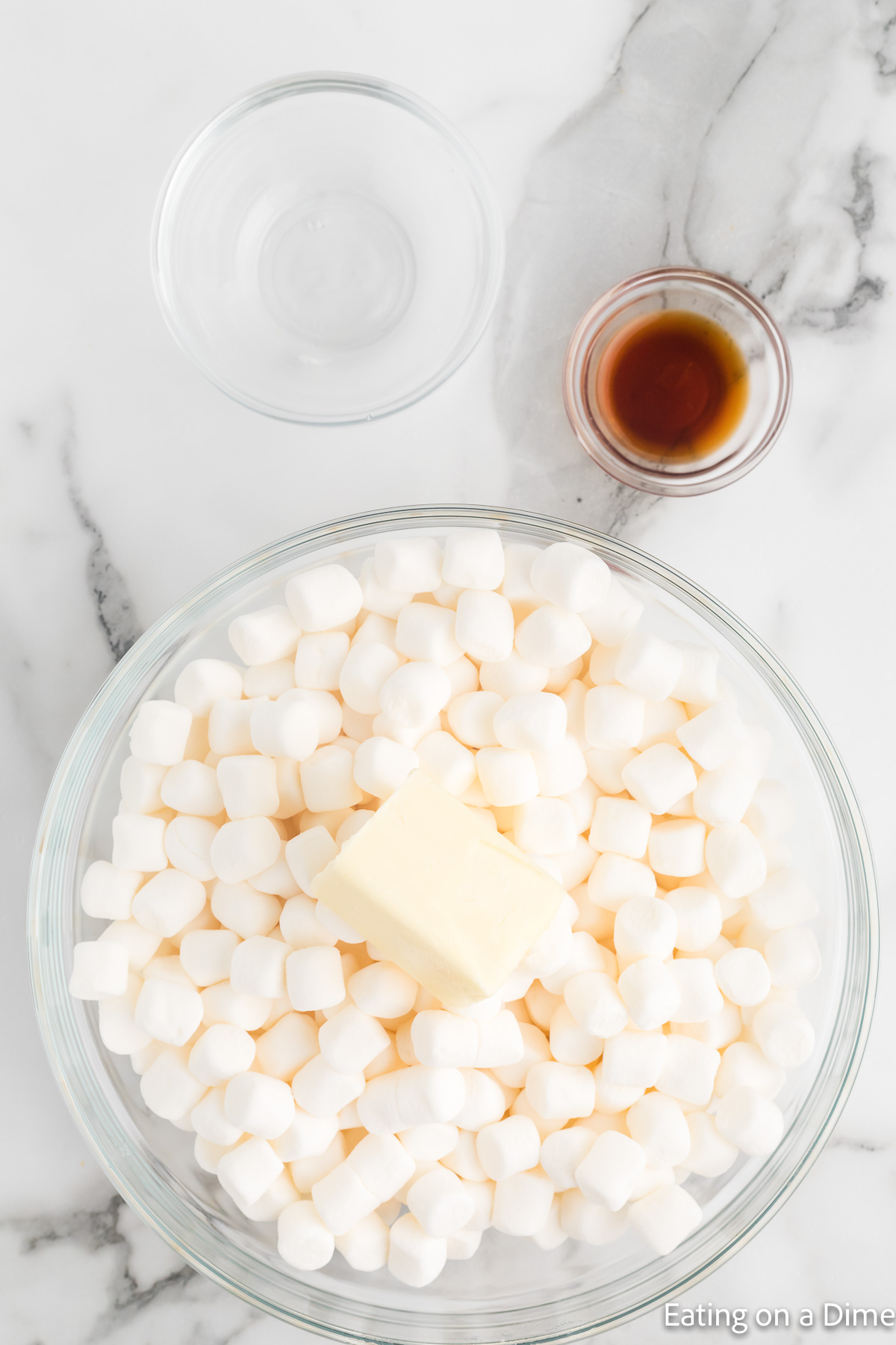 Placing marshmallows in a bowl with a stick of butter