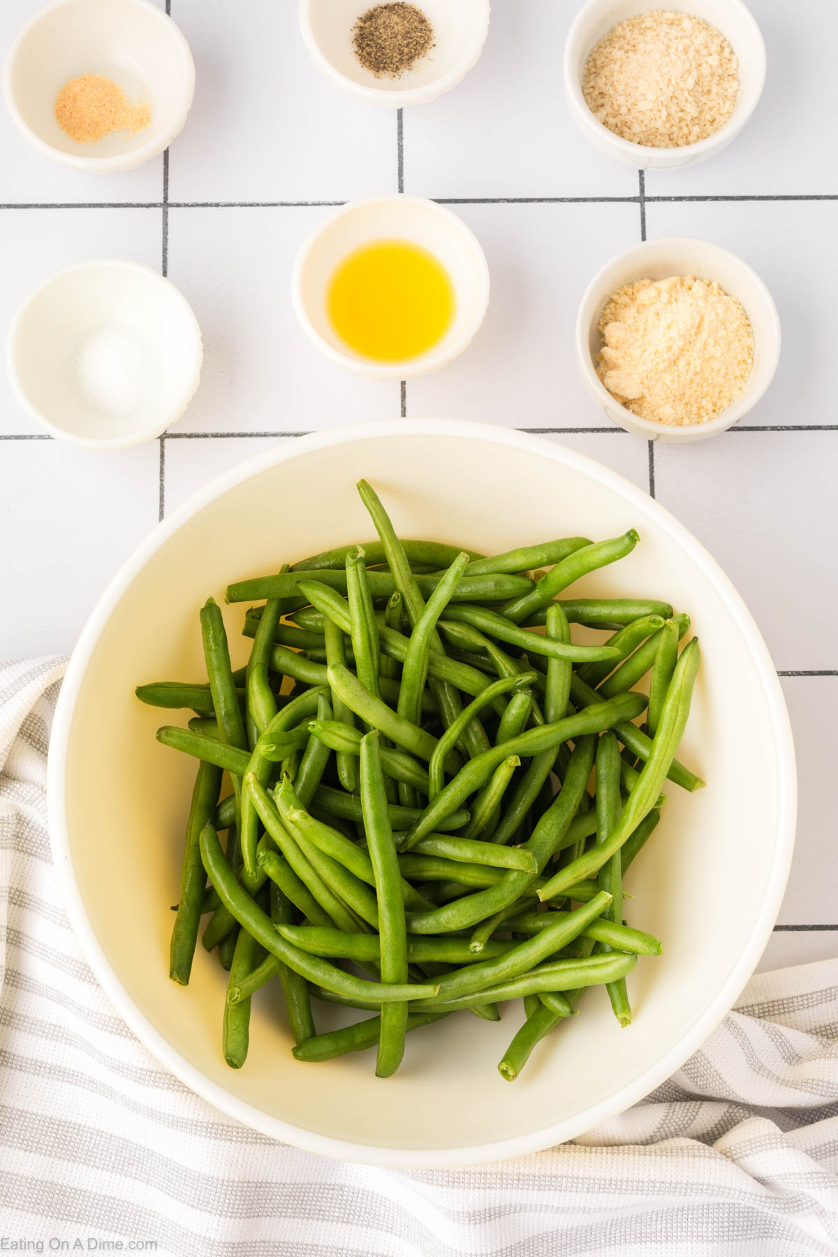 Fresh green beans in a bowl and seasoning in small bowls