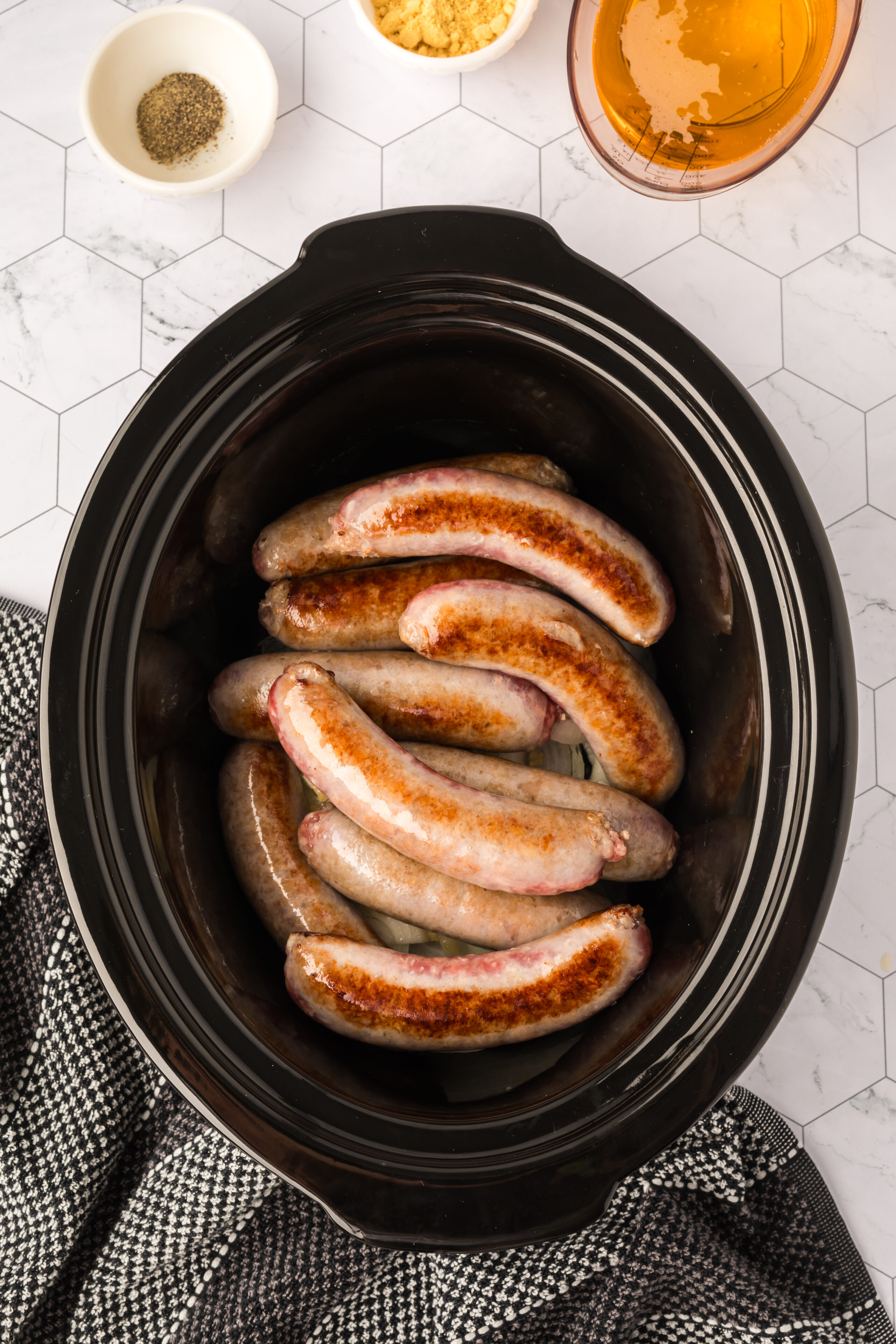 Placing the seared brats in the slow cooker