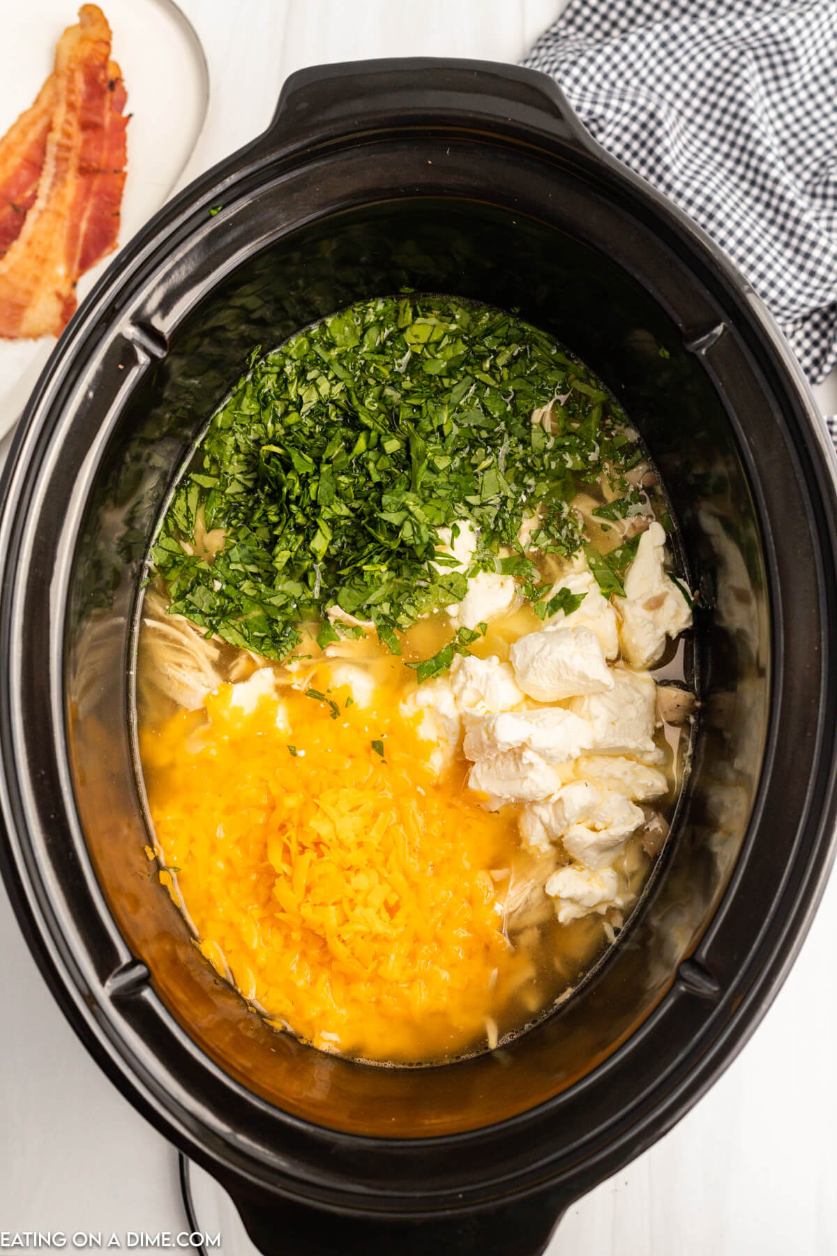 Mixing in the cream cheese, cheese, and kale to the slow cooker