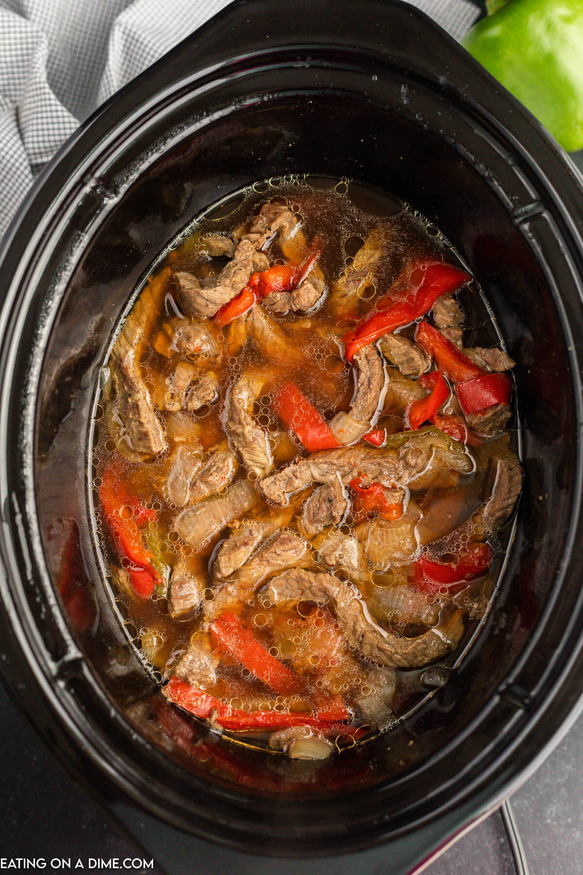 The sliced beef, bell peppers and sliced onions cooked in the crock pot.  