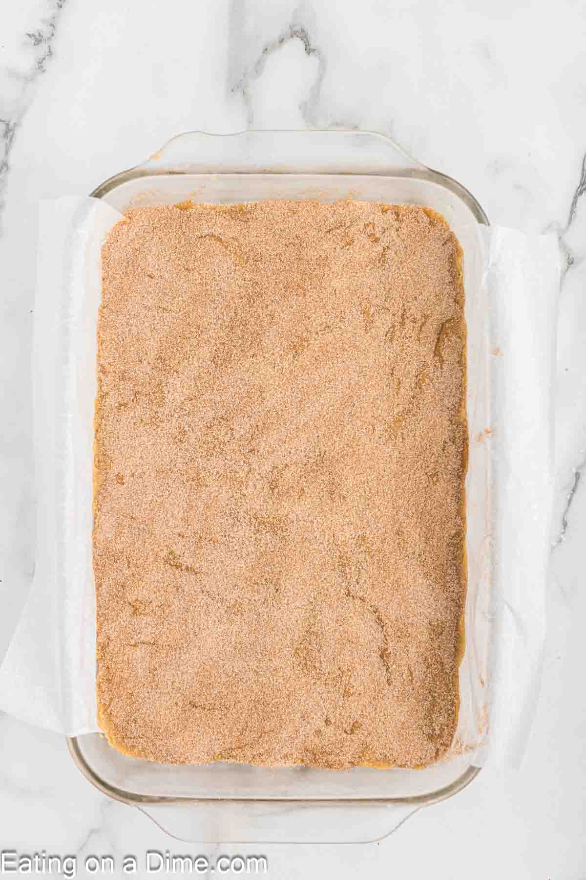 Spreading the blondie batter into the baking dish topped with a cinnamon sugar mixture