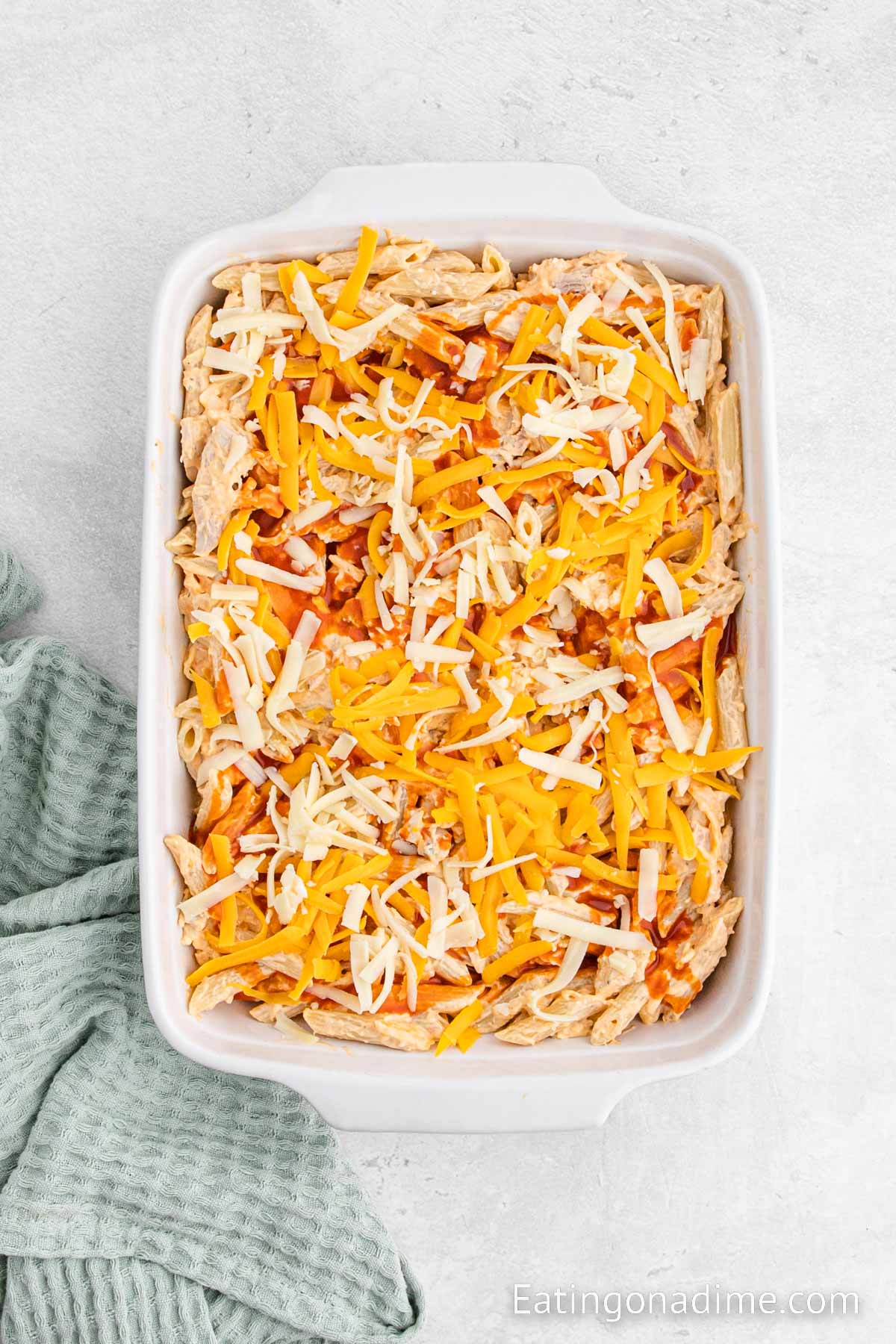 Topping the chicken mixture with shredded cheese