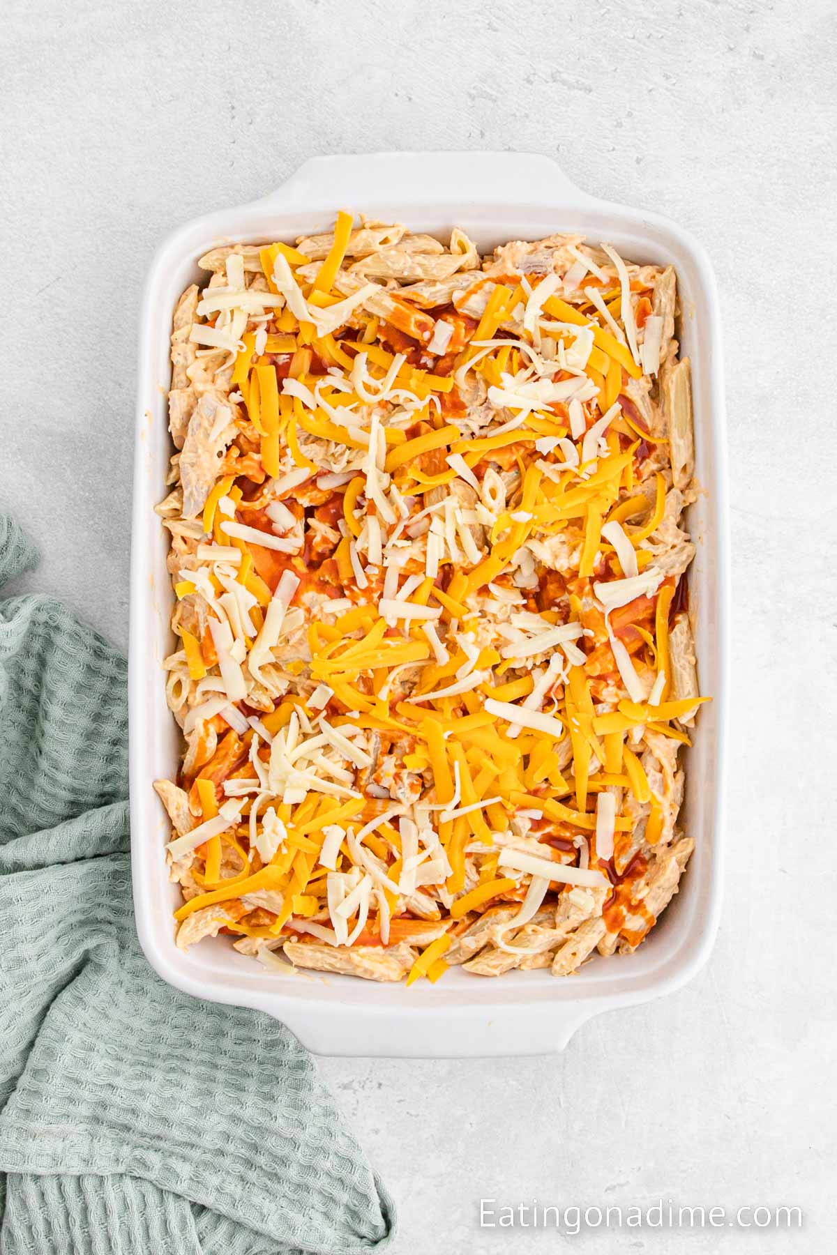 Topping the chicken mixture with shredded cheese