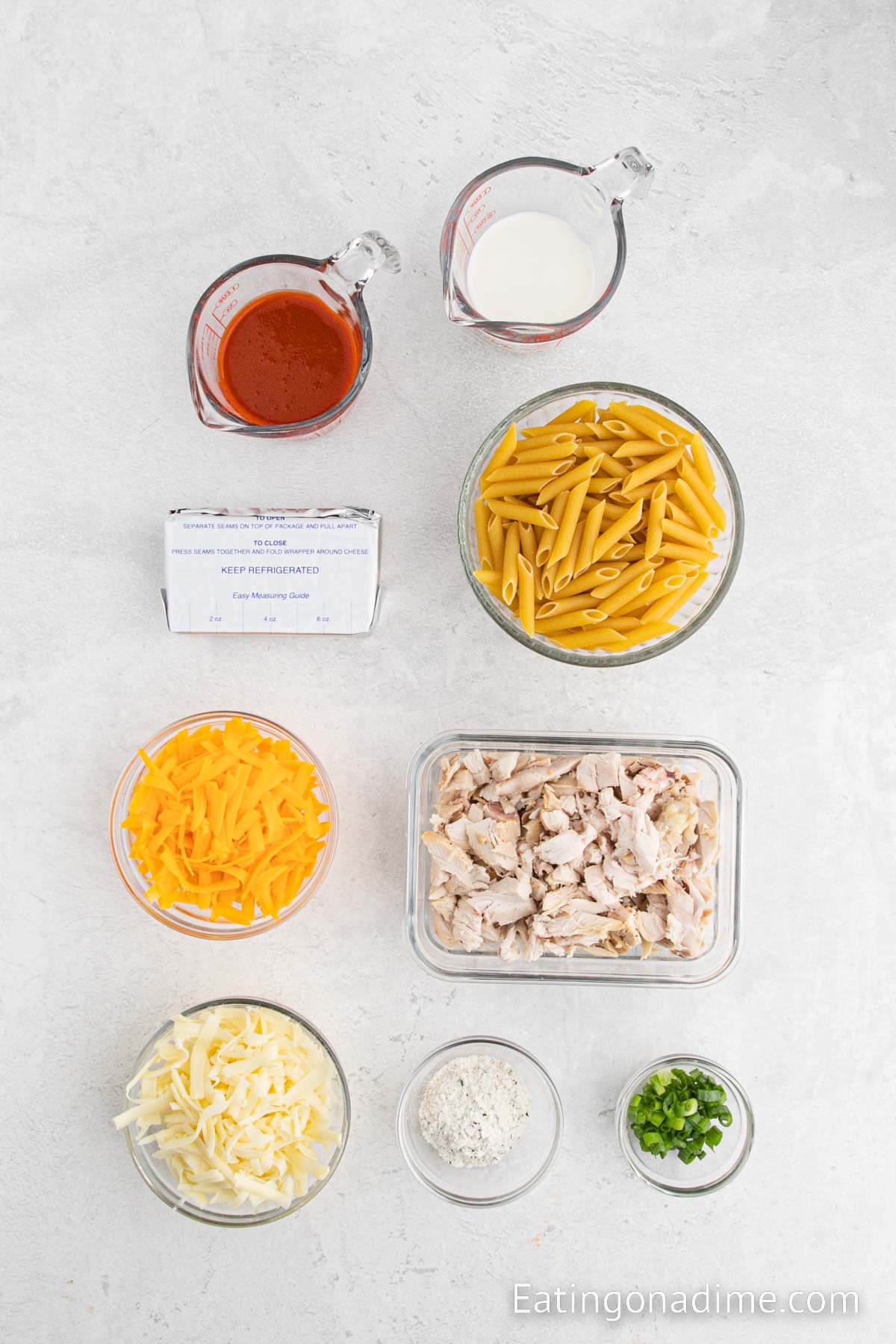 Buffalo chicken pasta bake ingredients - penne pasta, cream cheese, ranch seasoning mix, milk, buffalo sauce, chicken breasts, monterey jack cheese, cheddar cheese, green onions