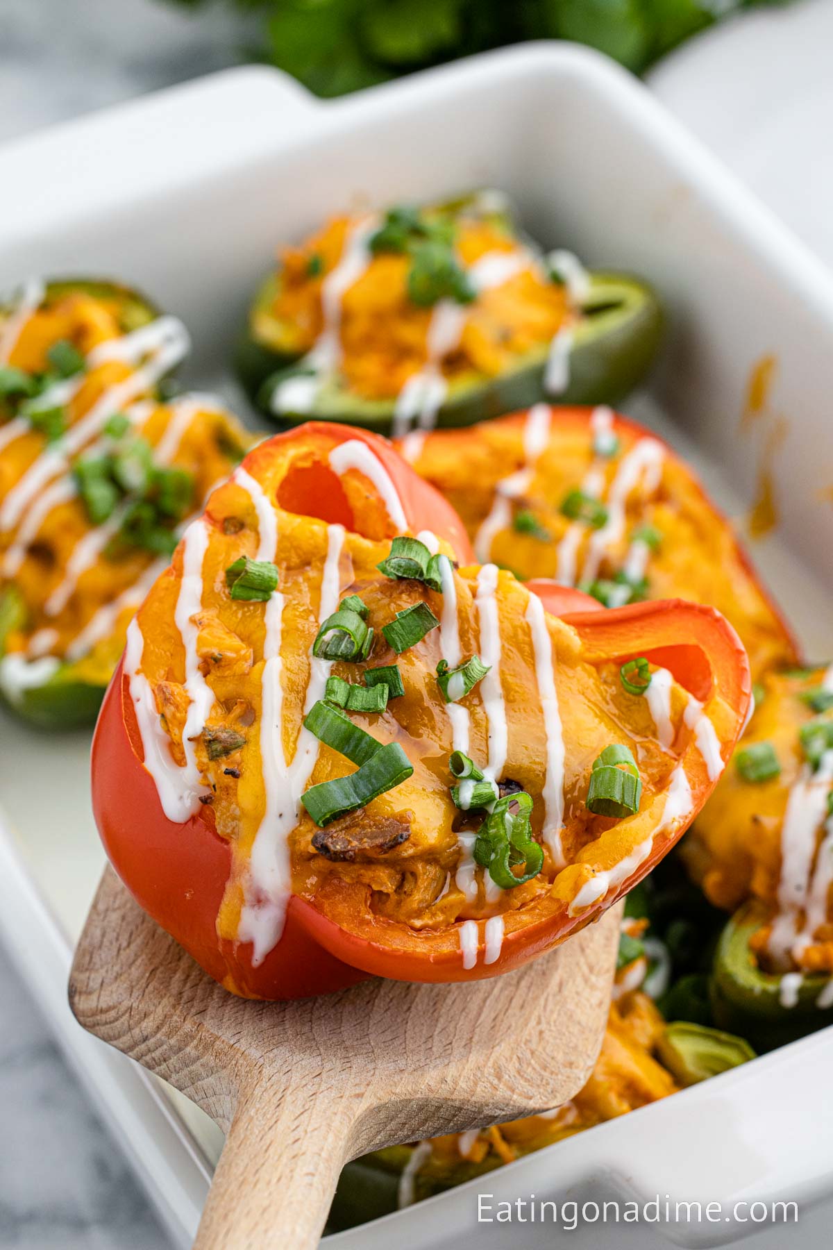 Close up image of buffalo chicken stuffed peppers with a serving on a wooden spatula
