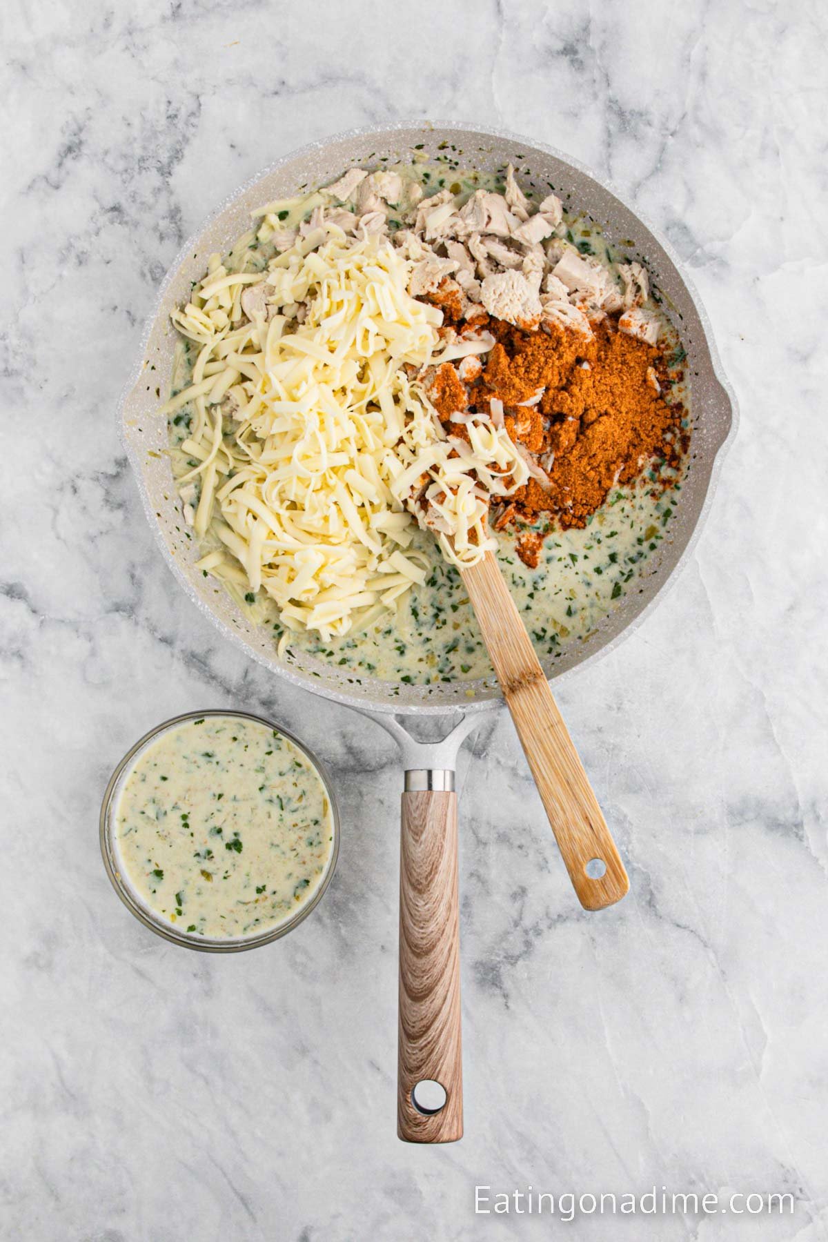 Heating the chicken, cheese and taco seasoning in a skillet with a wooden spoon