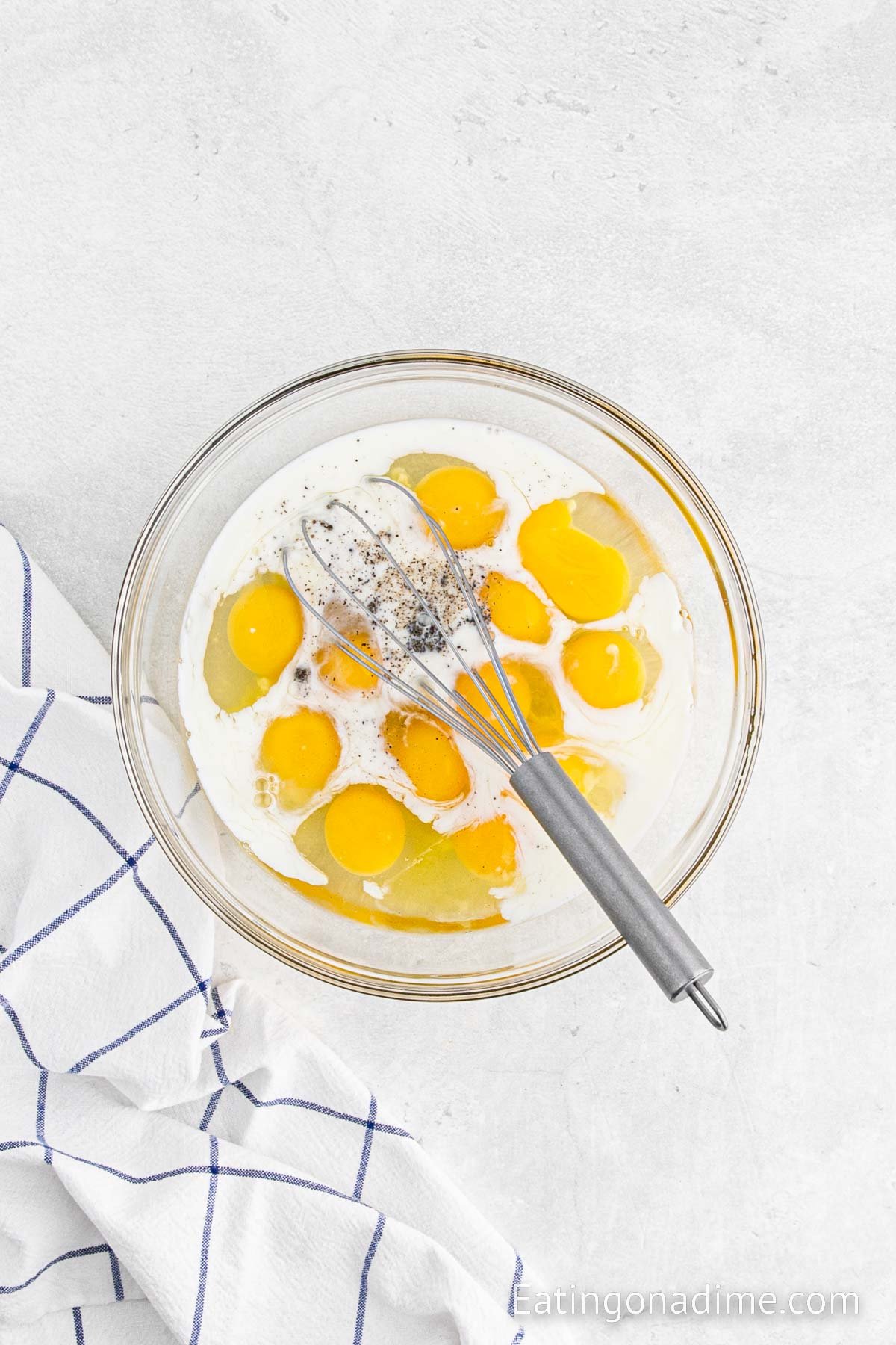 Whisking eggs, milk, and seasoning in a bowl