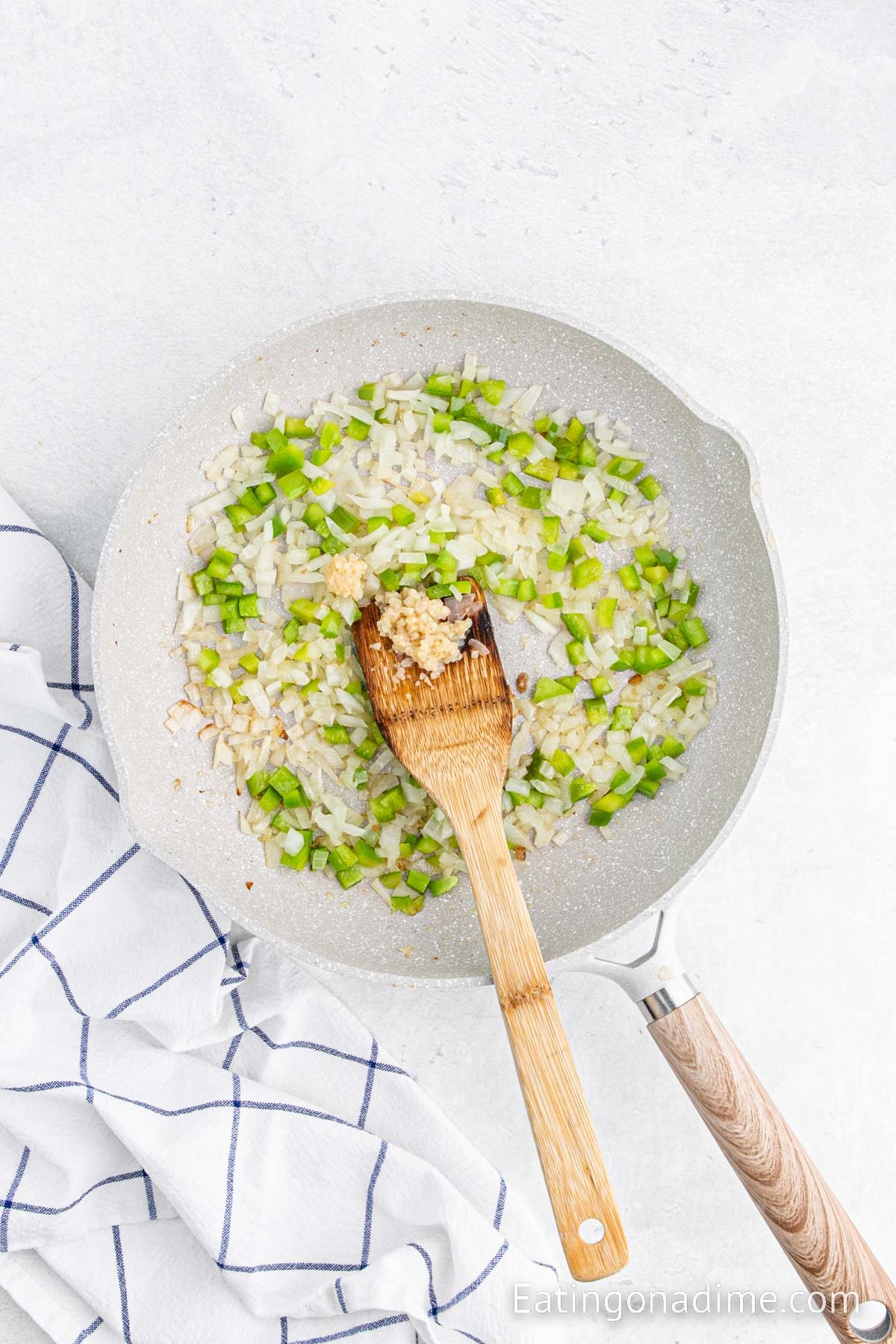 Cooking peppers and onions in a skillet with a wooden spoon