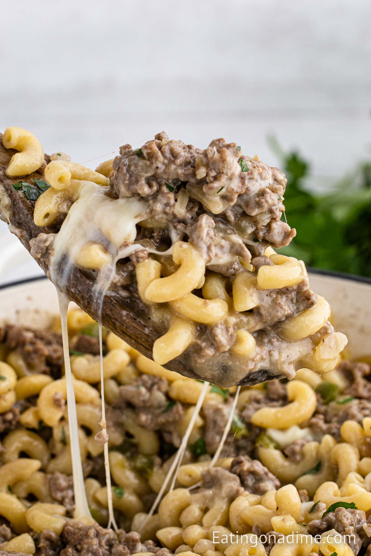 Skillet Philly Cheesesteak Pasta with a serving on the wooden spoon
