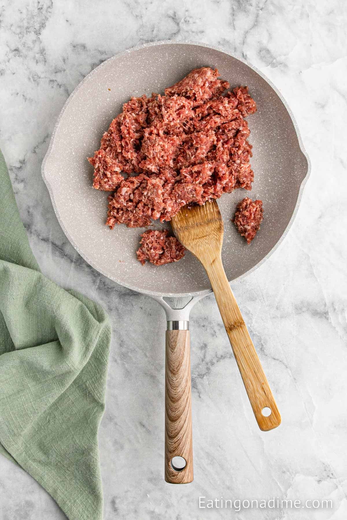 Cooking the sausage in a skillet with a wooden spoon