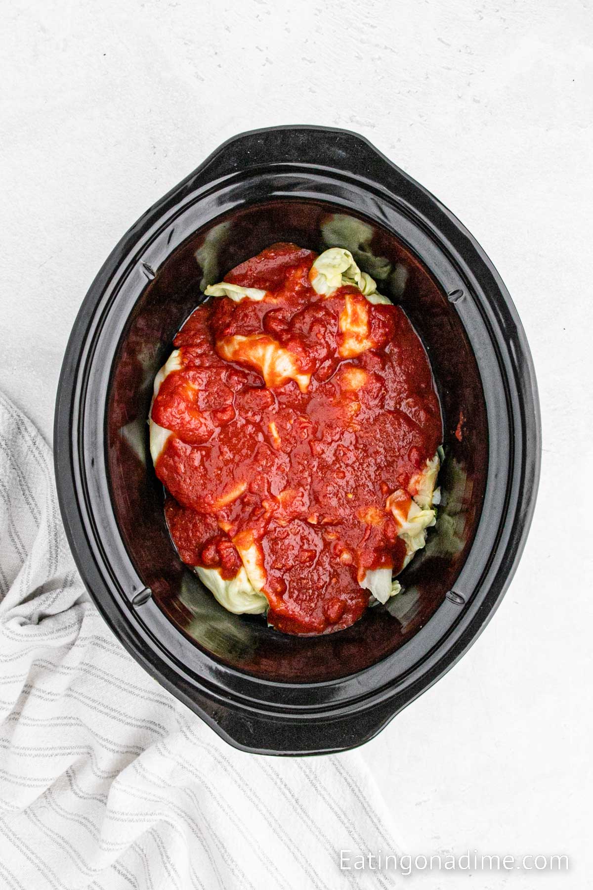 Placing the cabbage leaves and topping with sauce in the slow cooker