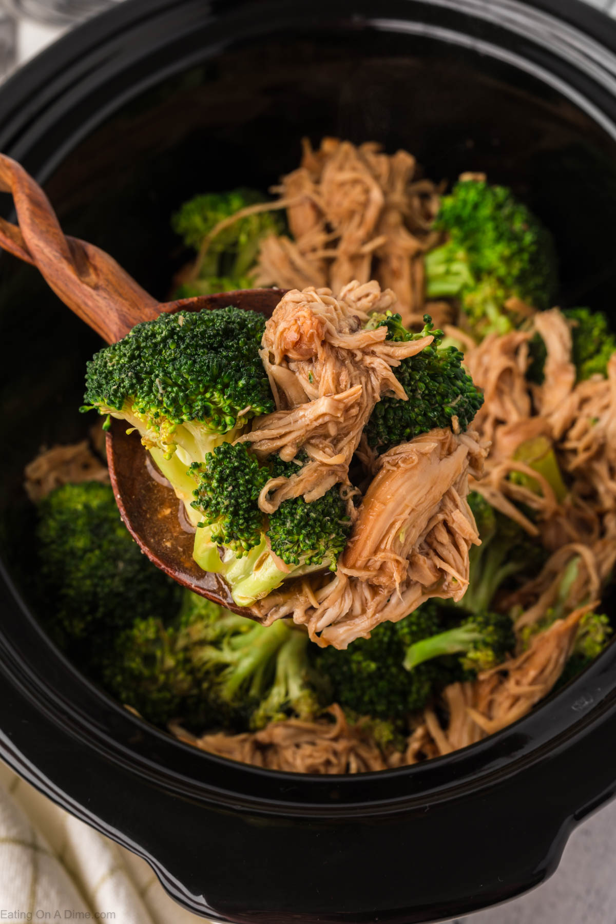 Close up image of chicken and broccoli on a wooden spoon