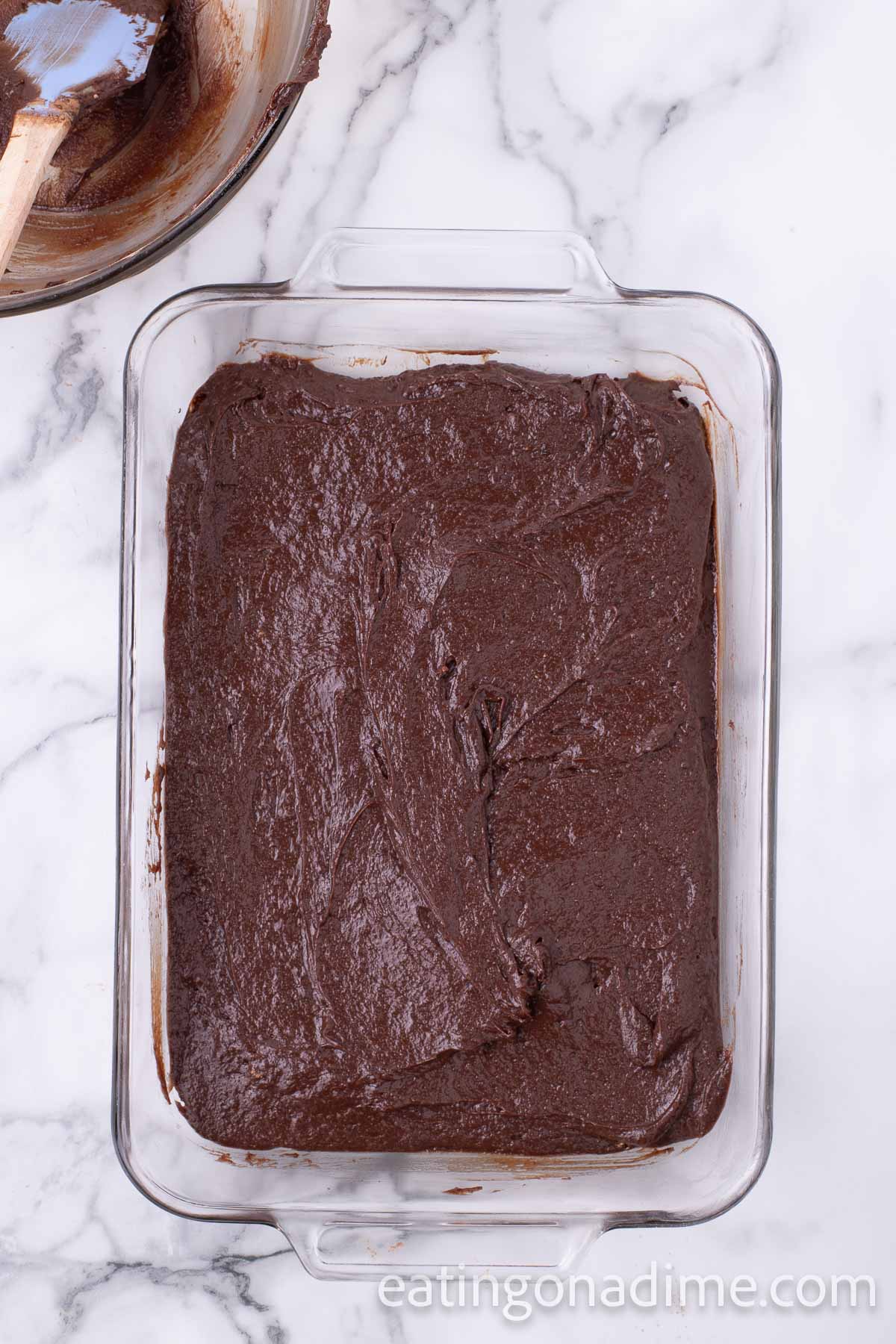 Brownie batter spread into a glass baking dish