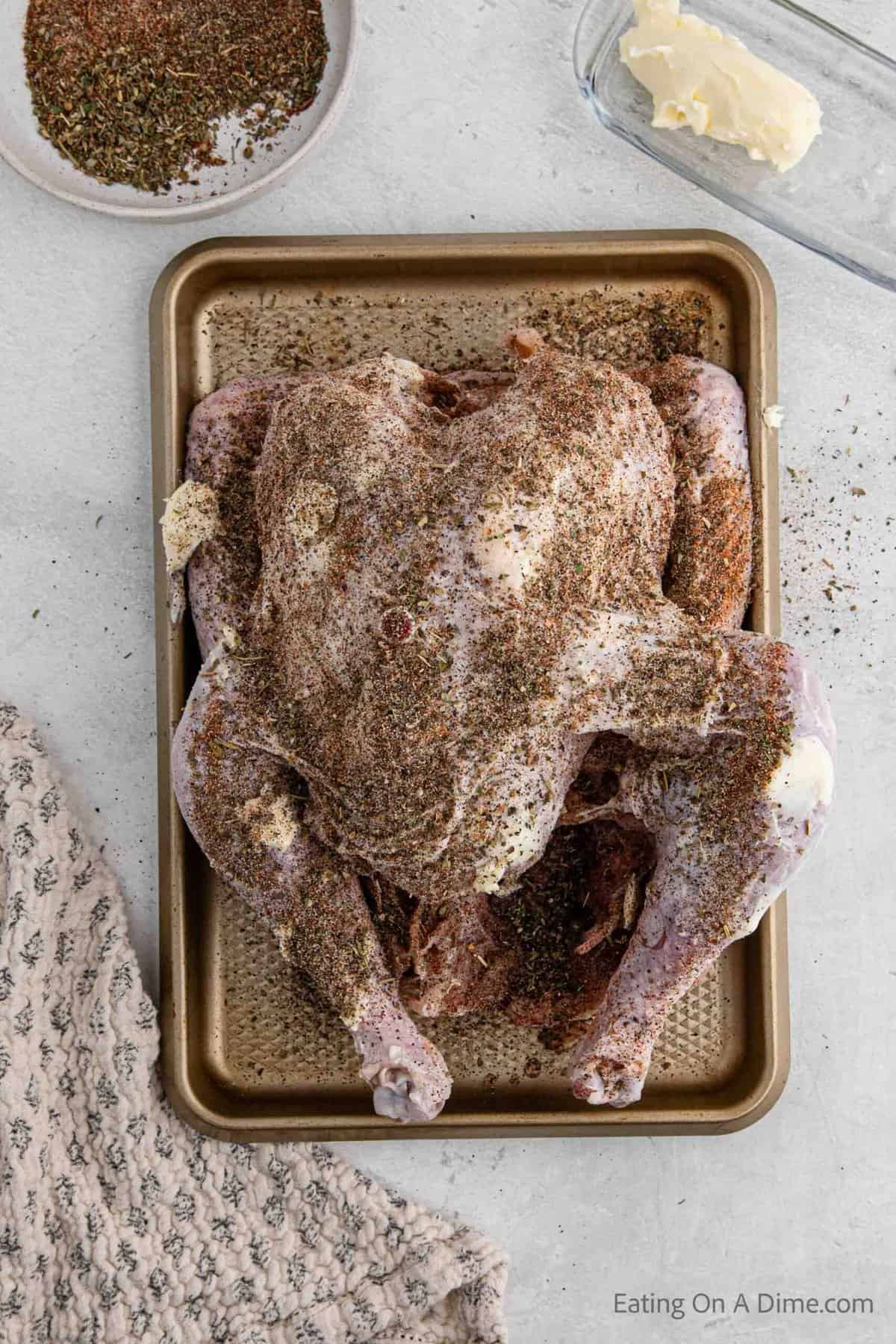 Rubbing the seasoning over the turkey on a baking sheet