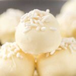 A close up of five white chocolate covered truffles.
