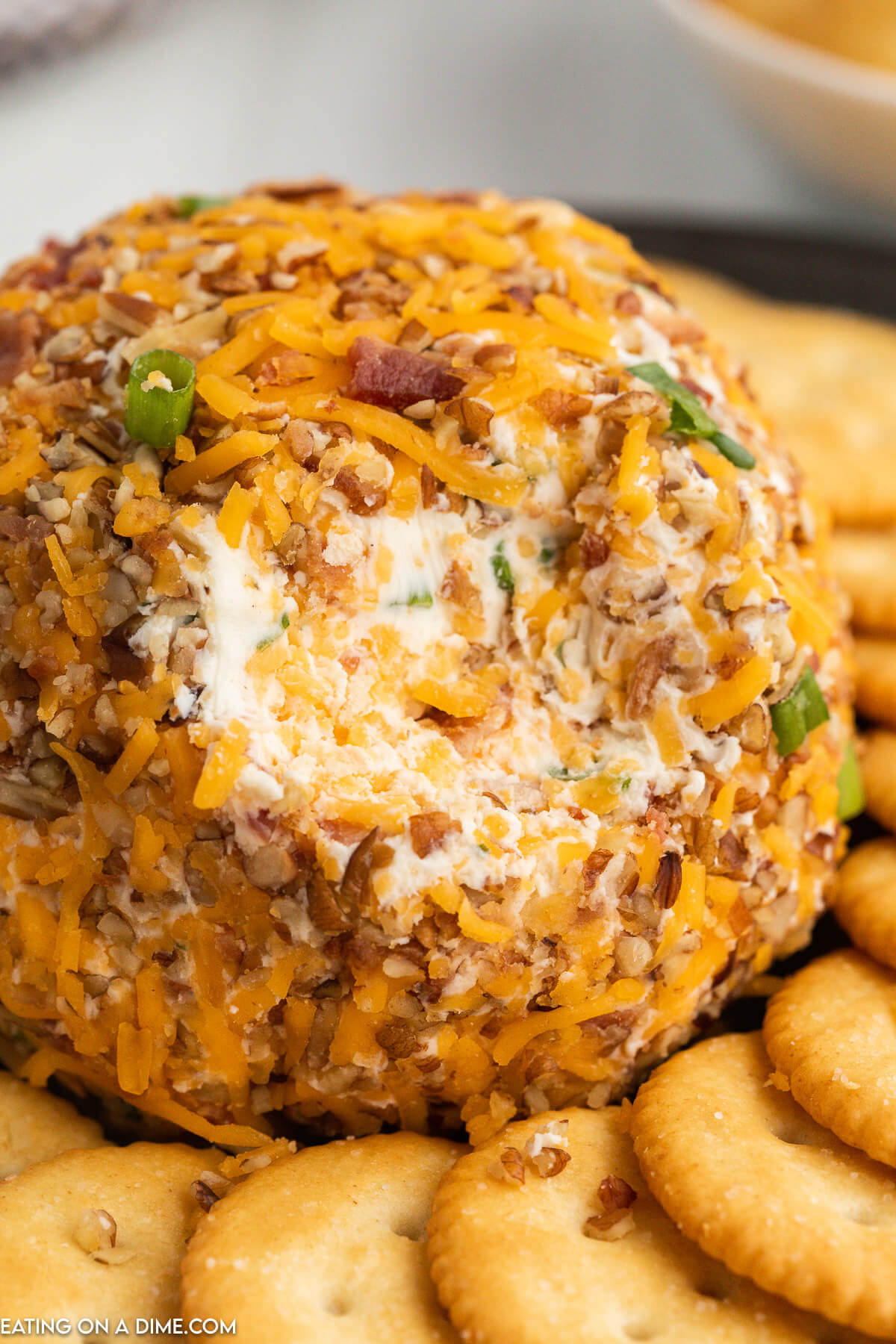 Close up image of bacon ranch cheese ball on a platter with crackers on the side