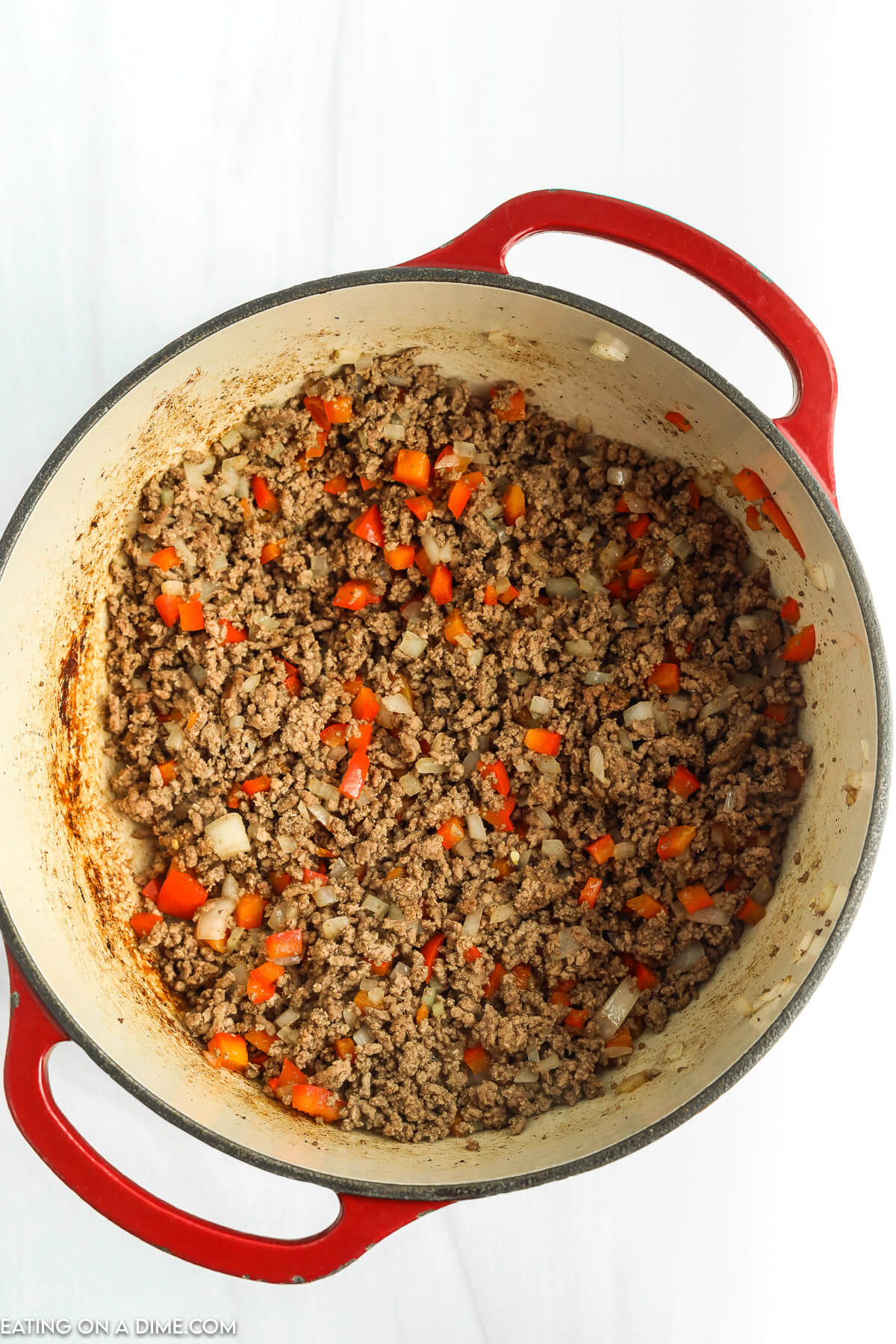 Adding the cut vegetables to the ground beef in a large pot
