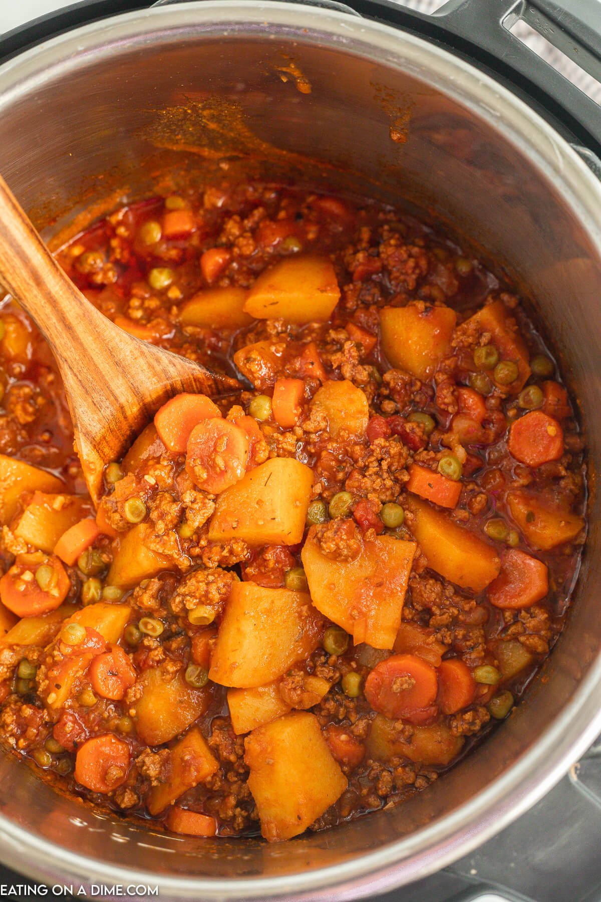 Ground Beef Stew in the pressure cooker with a wooden spoon