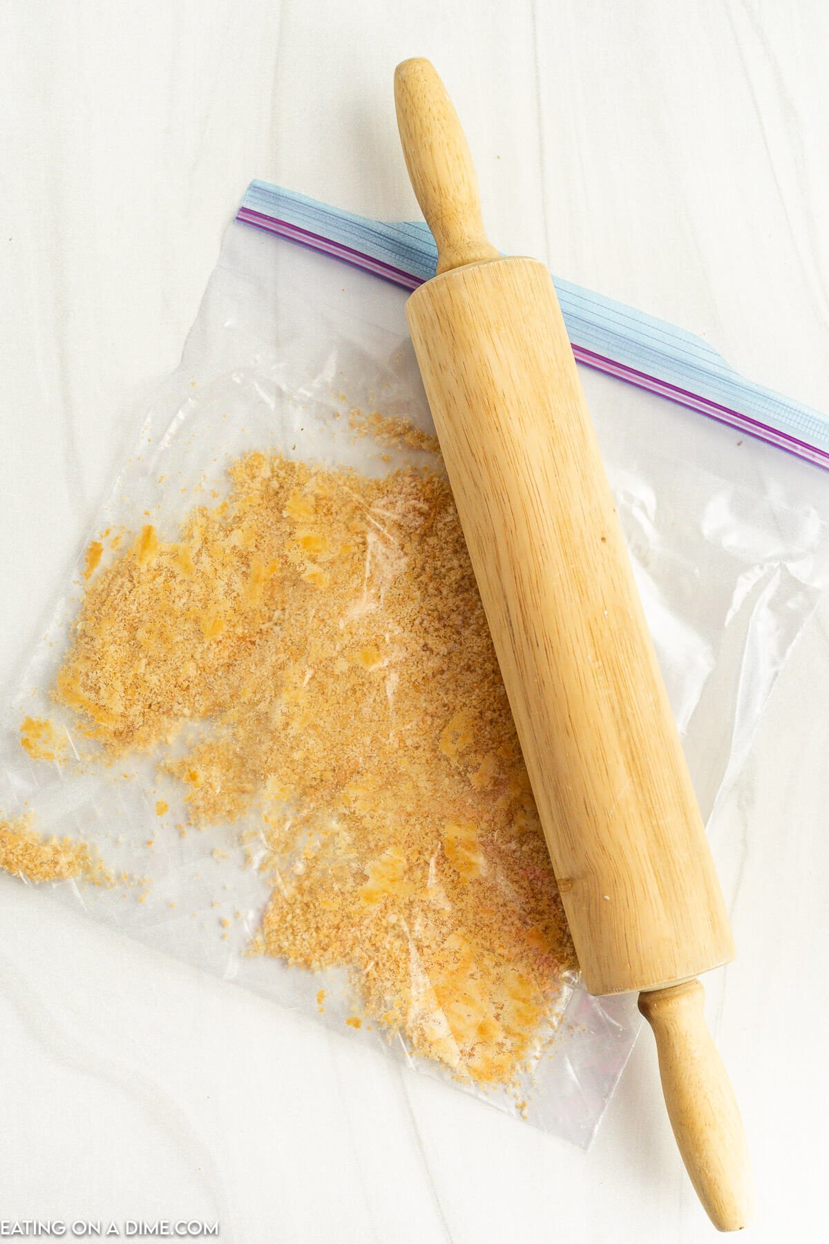 Crushing Ritz Crackers and parmesan with a rolling pin