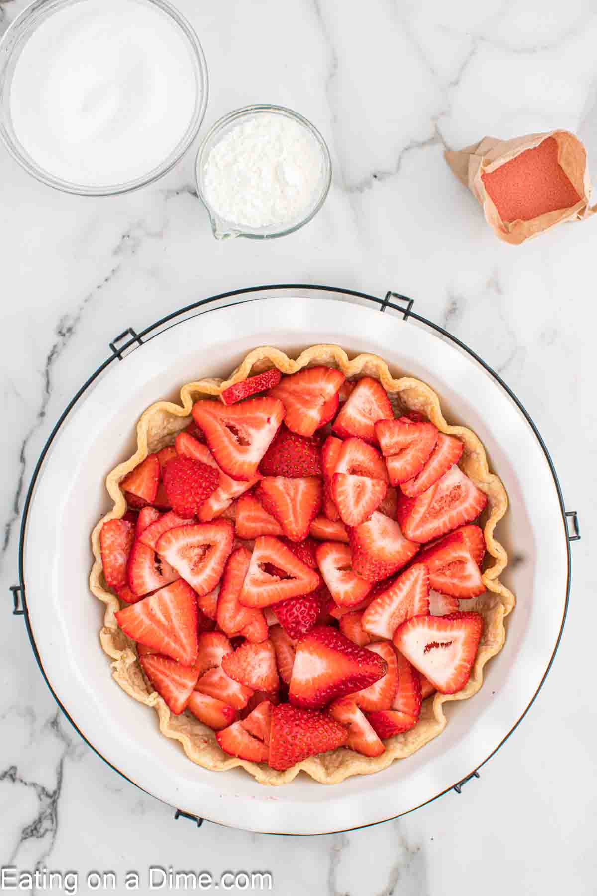 Layering slice strawberries in a pie crust
