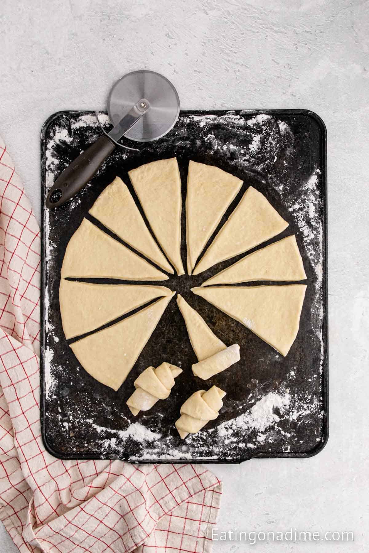 Rolling the triangle shaped dough on a floured surface